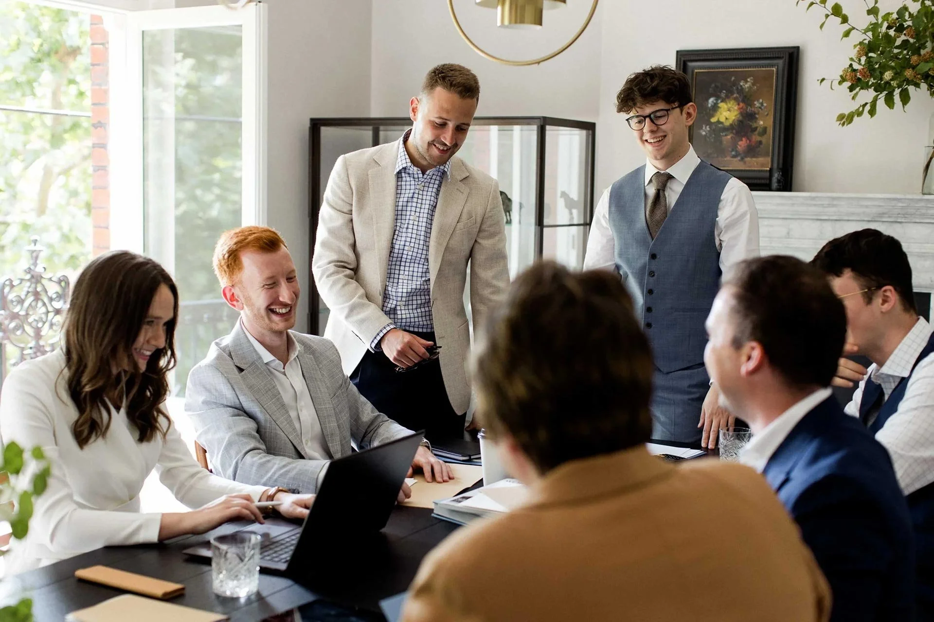 Group of men and women chartered accountants & business advisors laughing, smiling & sitting in an office in Mayfair, London