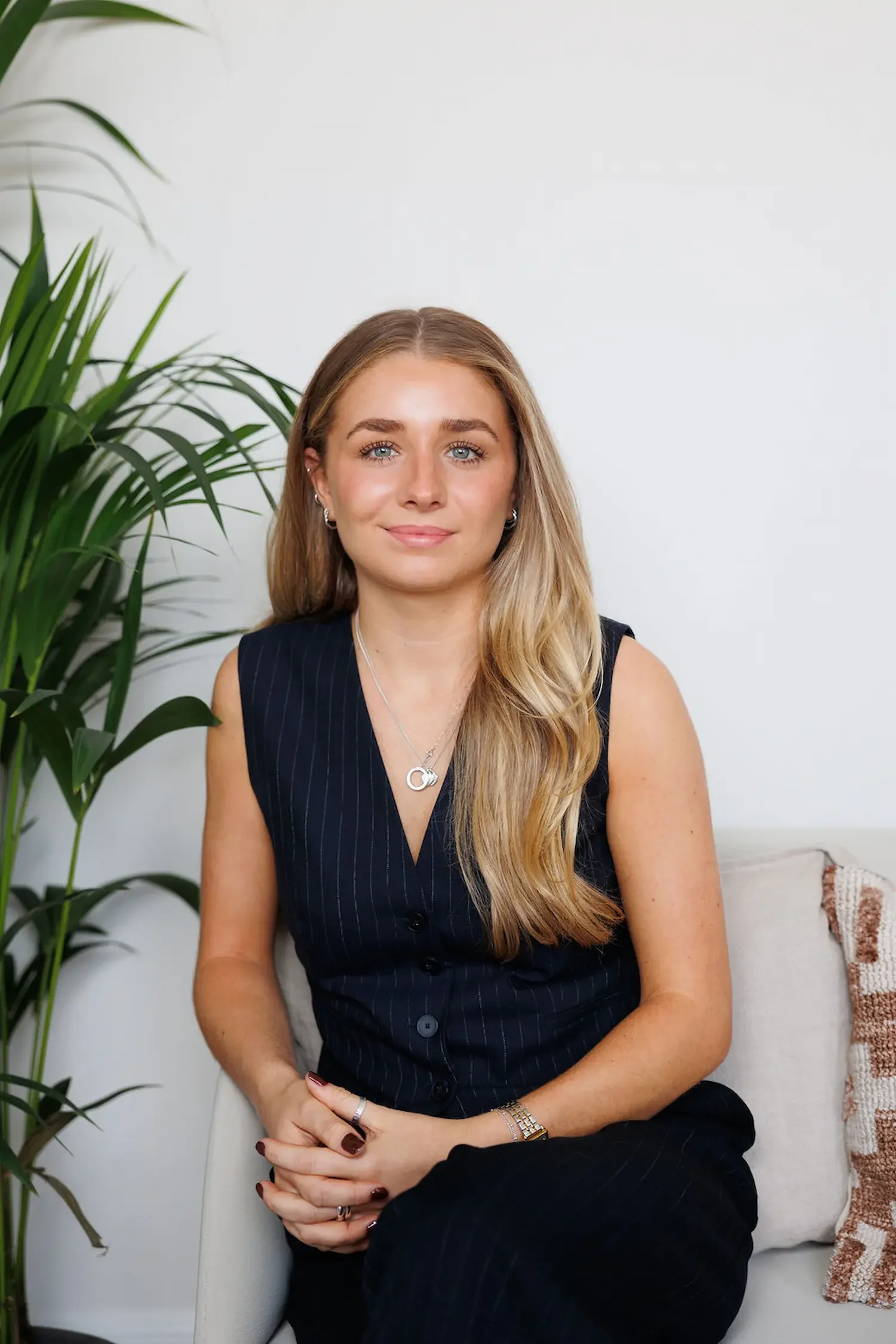 Sampson Fielding Assistant Tax Manager Alice Davies CTA smiling and sat on a sofa at their Central London accountancy office