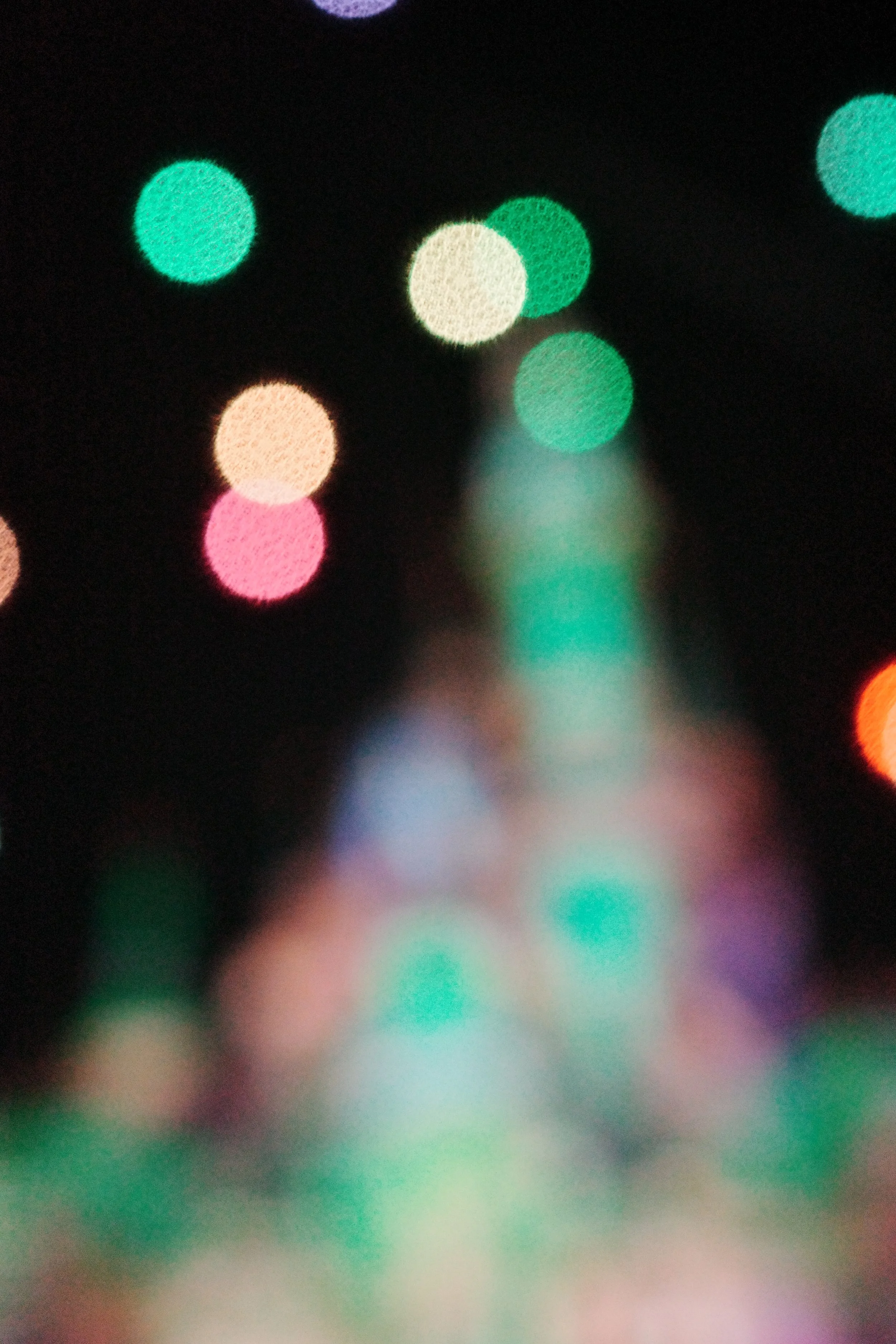 Blurred colorful lights on a dark background, resembling a bokeh effect.