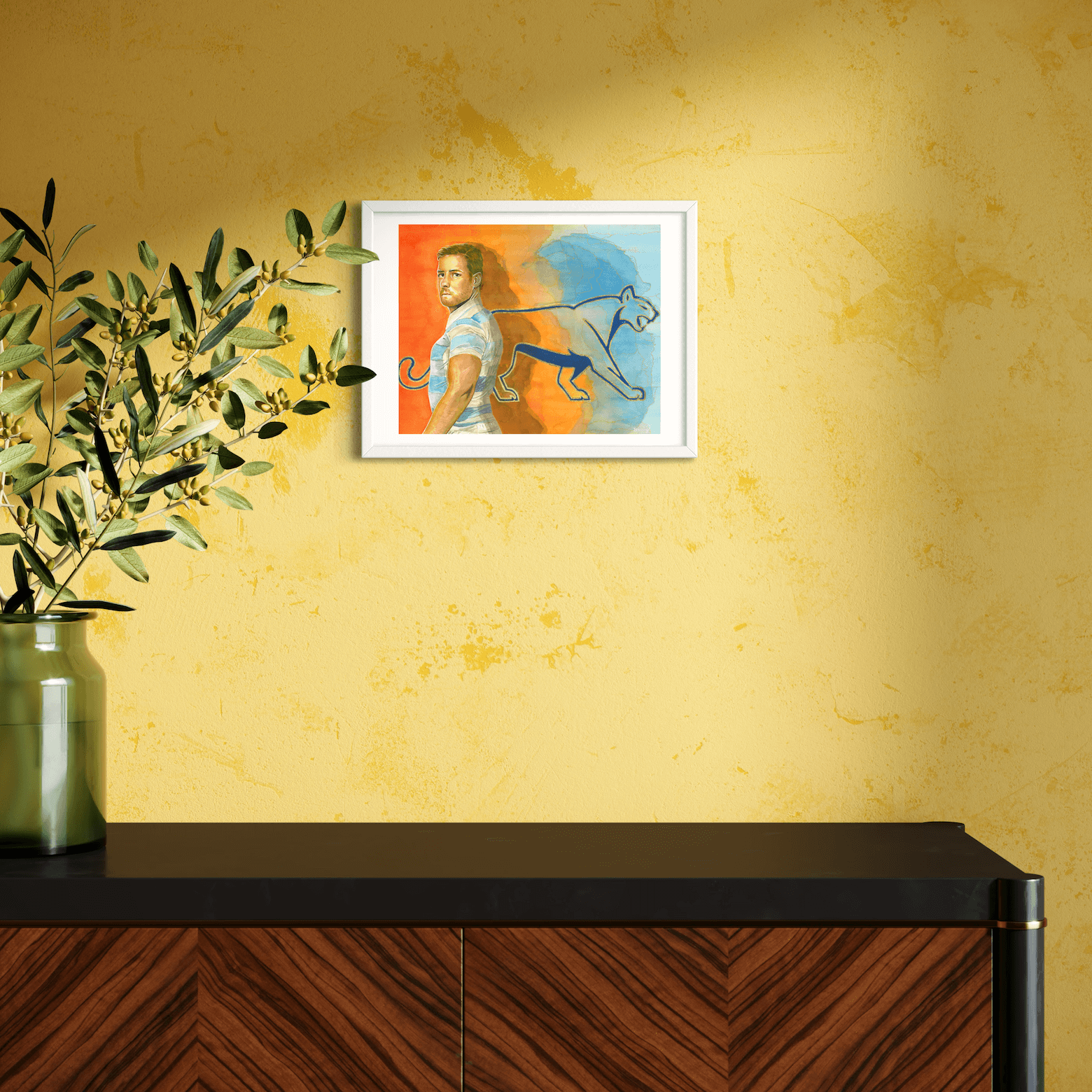 30 x 40 cm hand-embellished fine art print of Argentinian rugby player Nicolás Sánchez, displayed in a white frame without mat, mounted on a yellow wall above a modern wooden console.