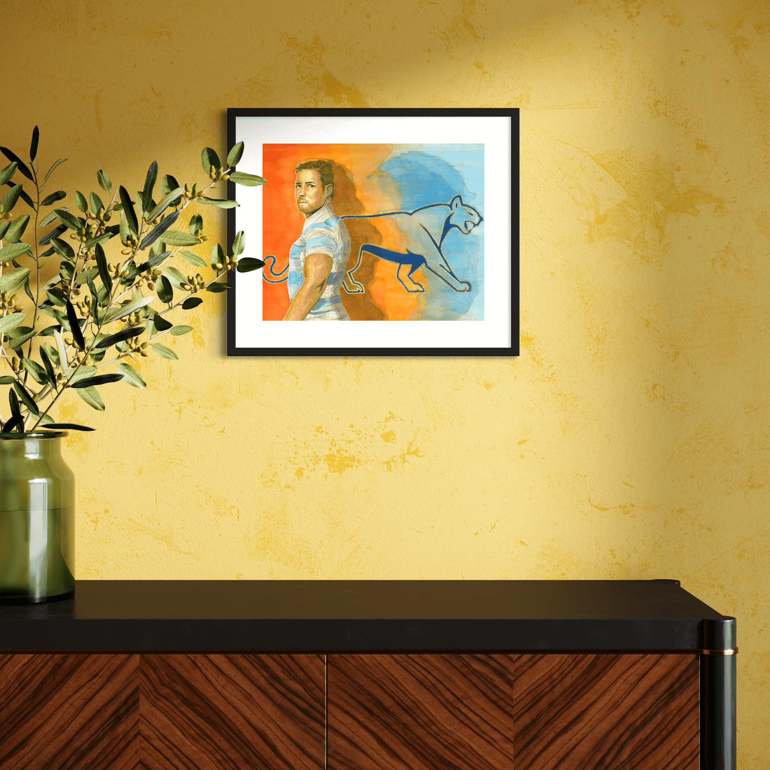 Custom framed, hand-embellished fine art print of Argentinian rugby player Nicolás Sánchez, displayed in a black frame with custom mat, mounted on a yellow wall above a modern wooden console.