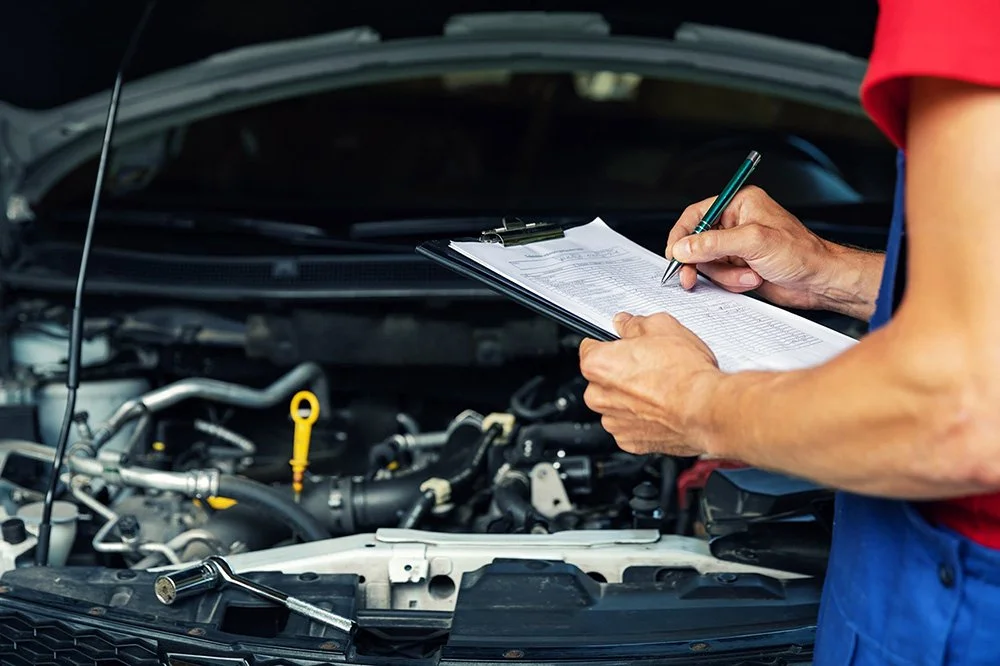 Mechanic completing diagnostic inspection checklist in front of vehicle engine.