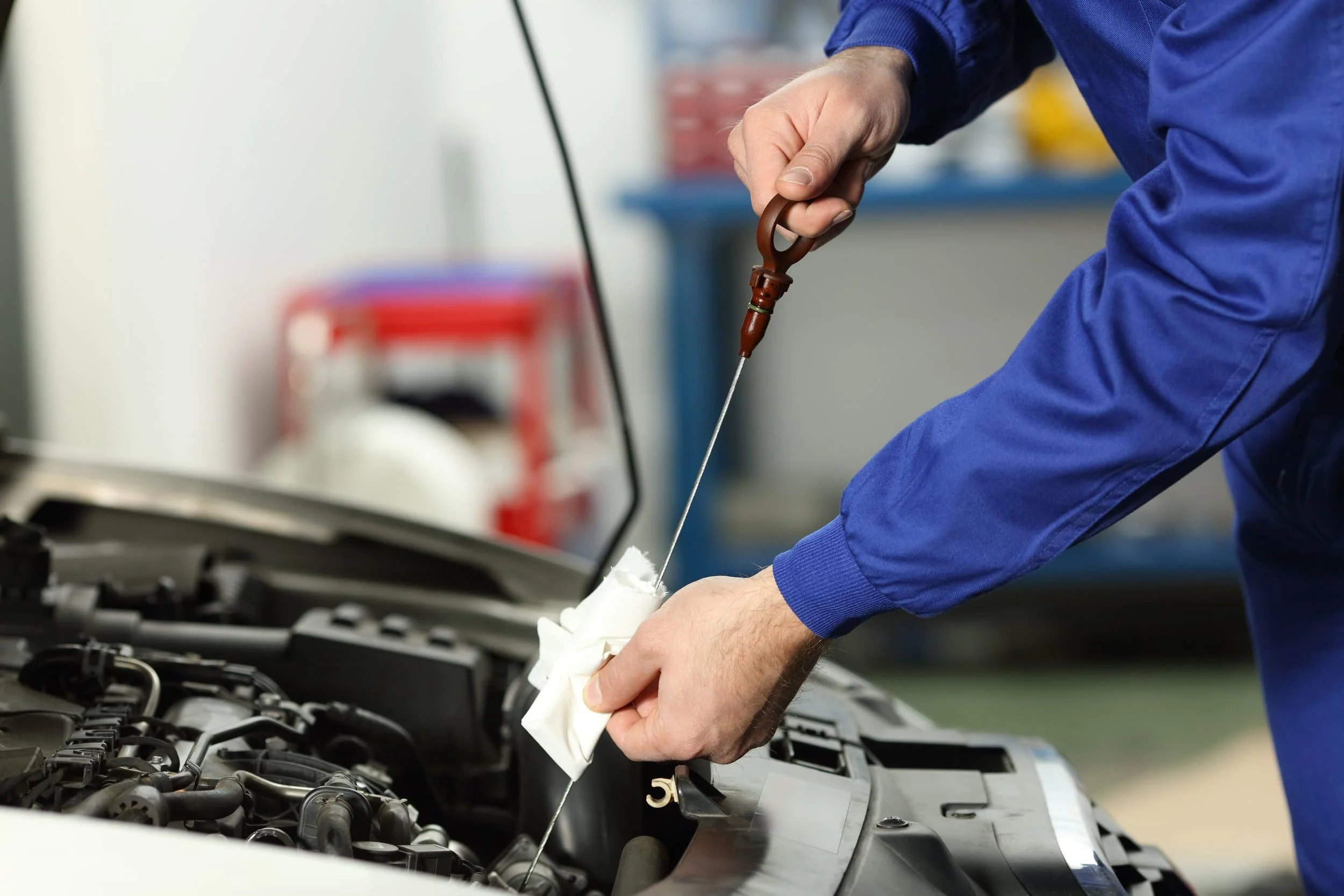 ualified mechanic checking engine oil level as part of a vehicle logbook service.
