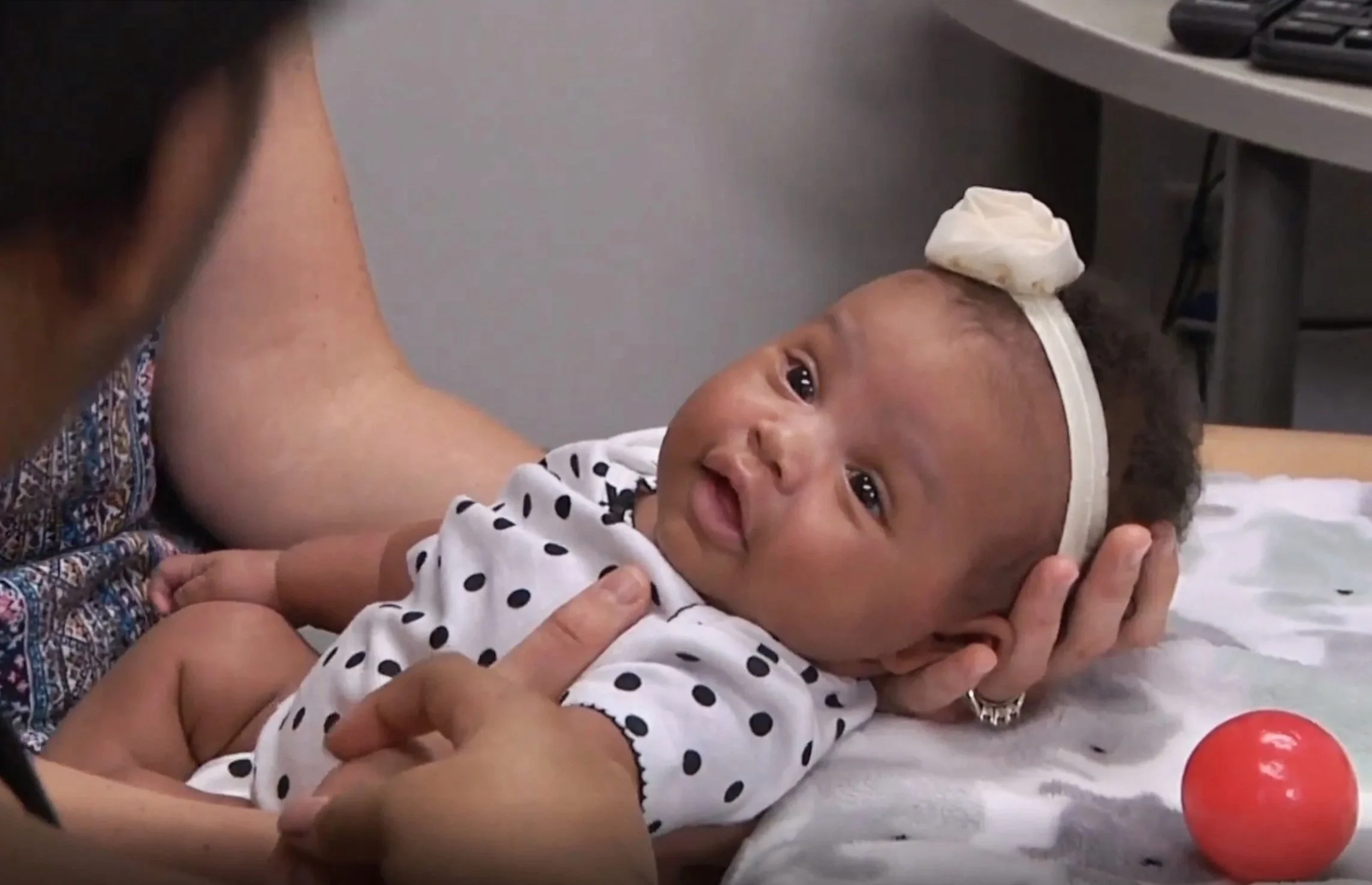 NBO trainers demonstrating newborn observation techniques with infant during hands-on training session. NBO demonstration, newborn care training, hands-on clinical training