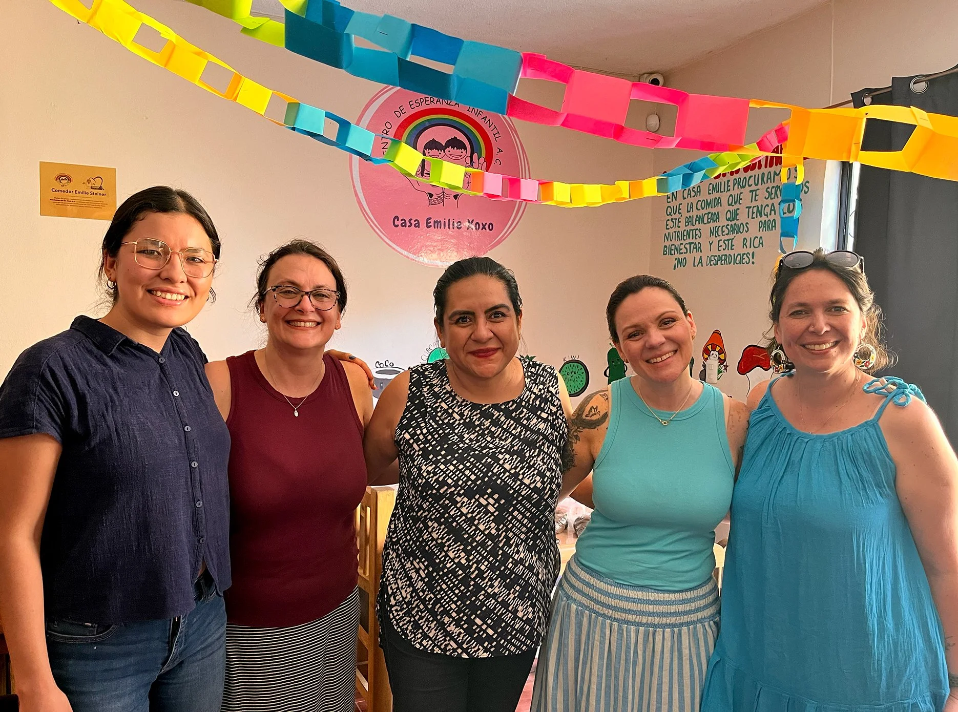 The team standing together and smiling in a community space, reflecting collaboration, shared purpose, and a team rooted in real-world relationships.