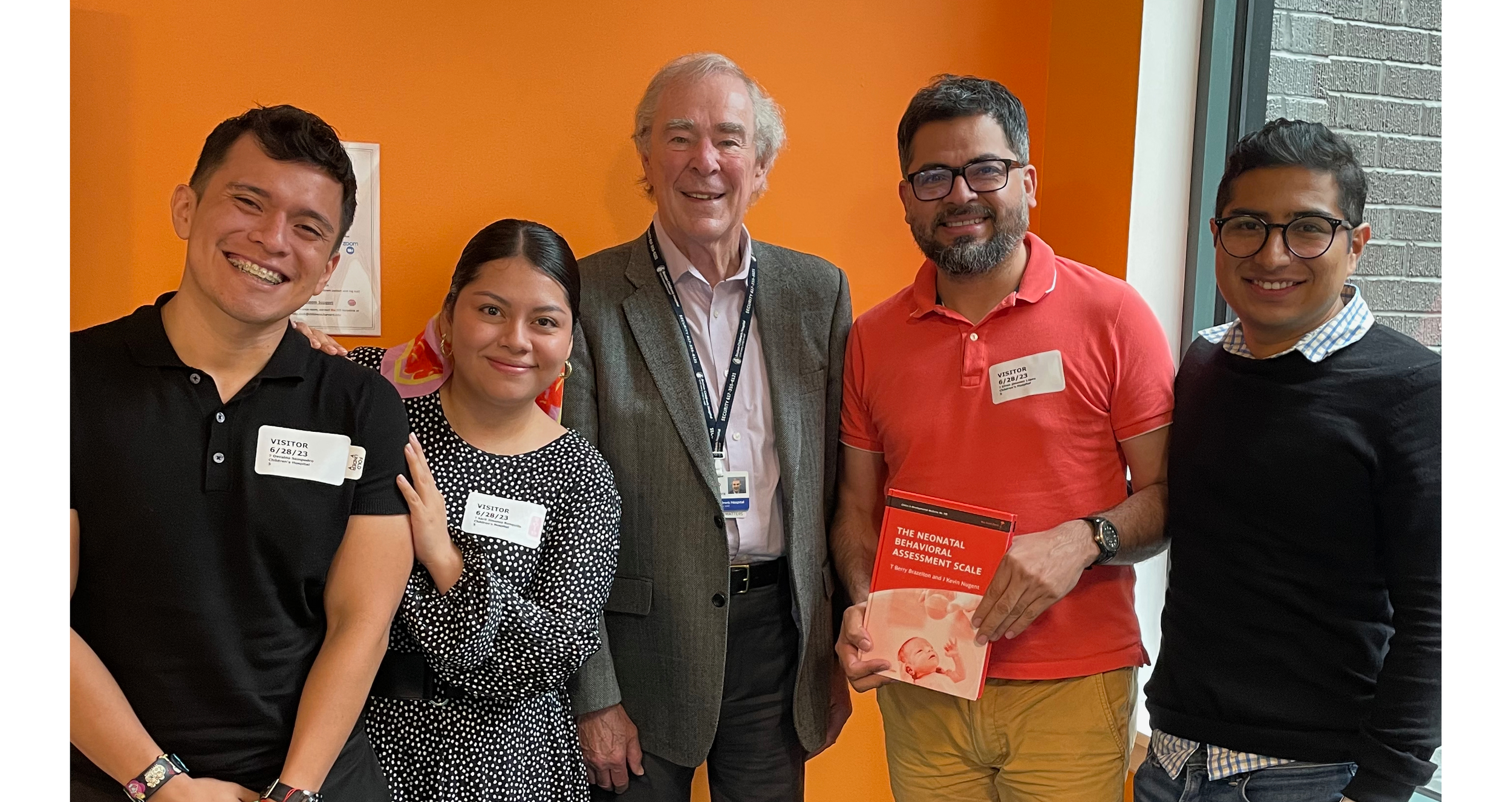 Dr. Kevin Nugent and a small group of practitioners standing together and smiling at a professional event, with one person holding a book on newborn assessment, reflecting shared learning and collaboration.