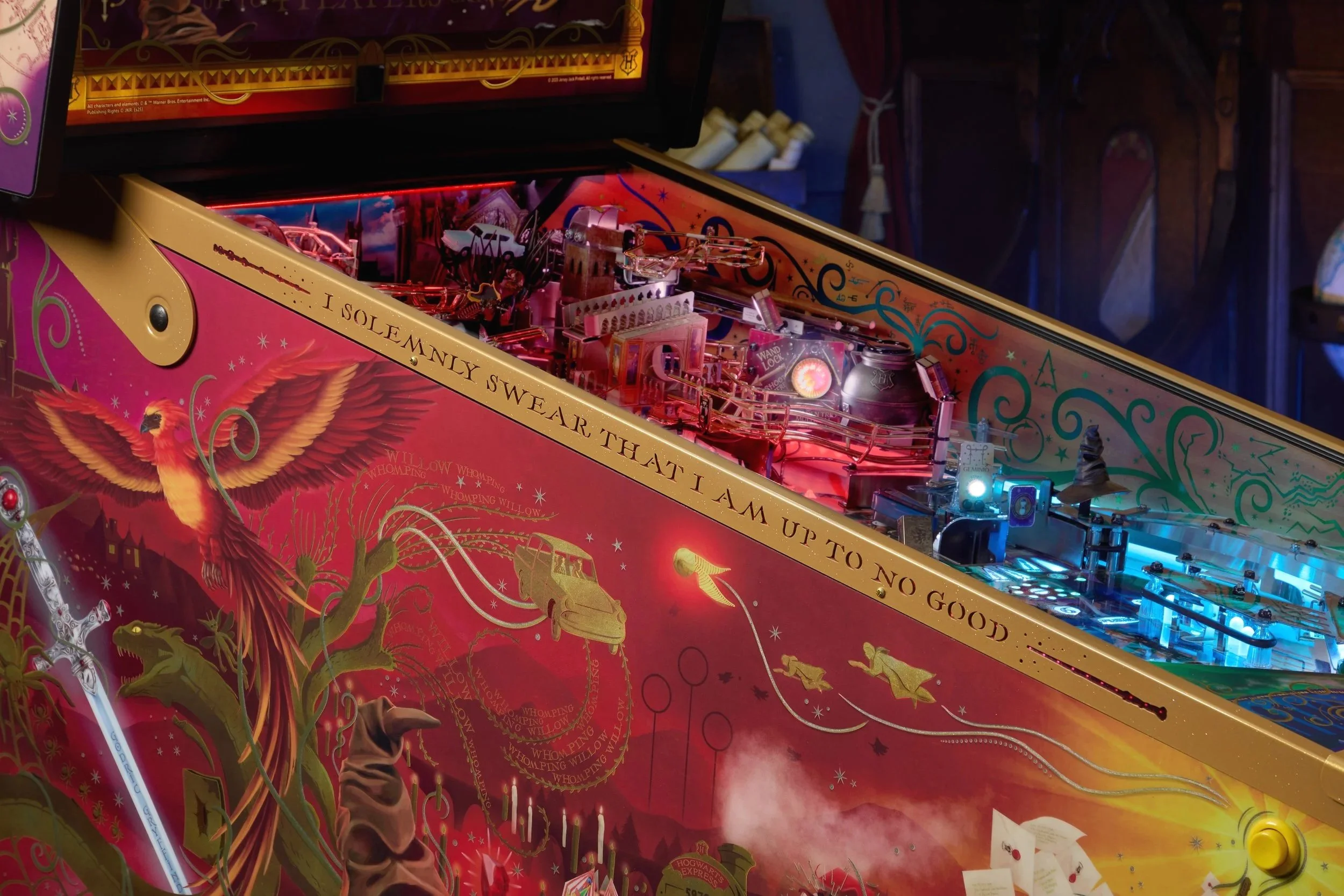 Close-up of a Harry Potter-themed pinball machine with decorative artwork and lights.