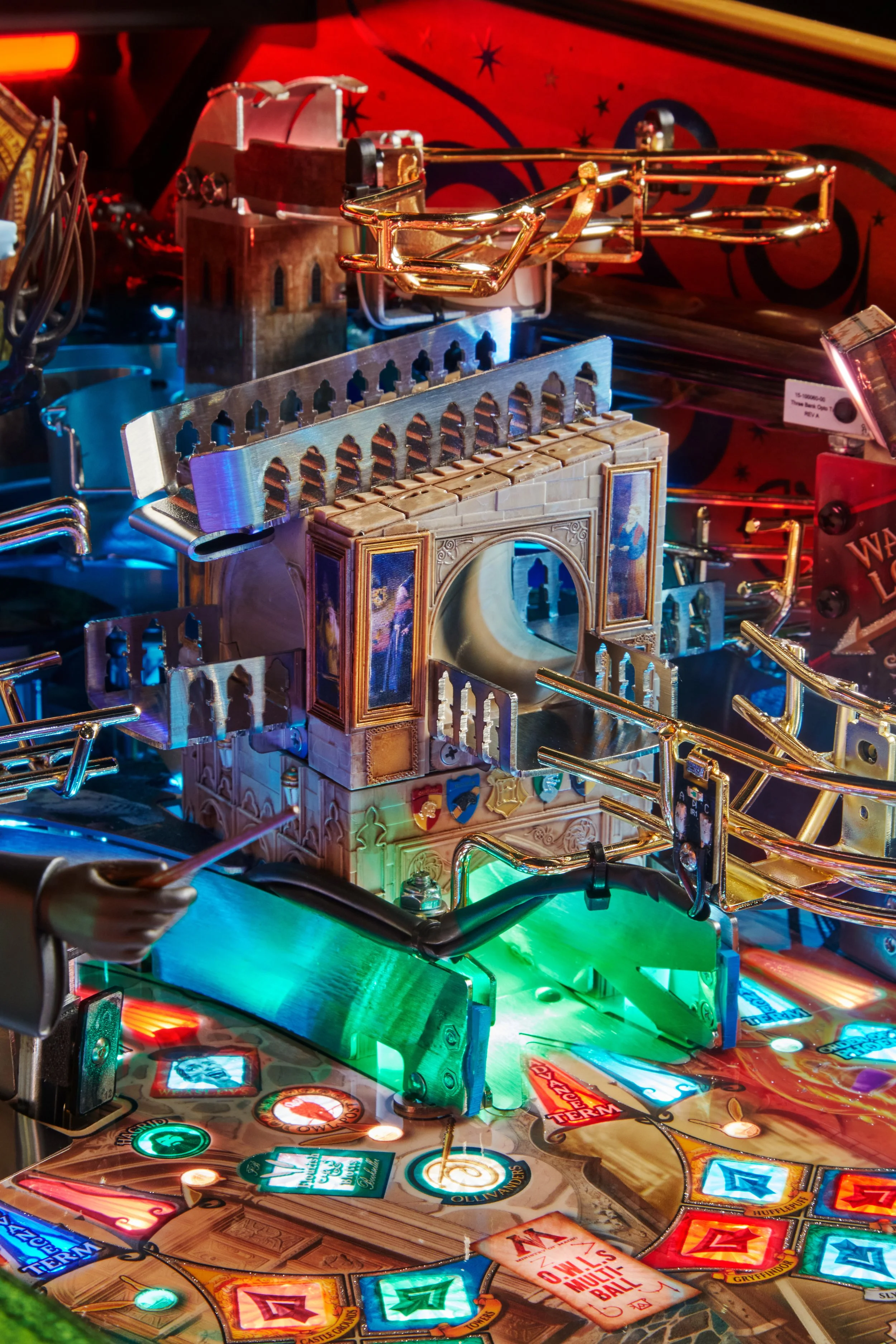 Close-up view of a Harry Potter-themed pinball machine with colorful lights, detailed artwork, and metallic bumpers.