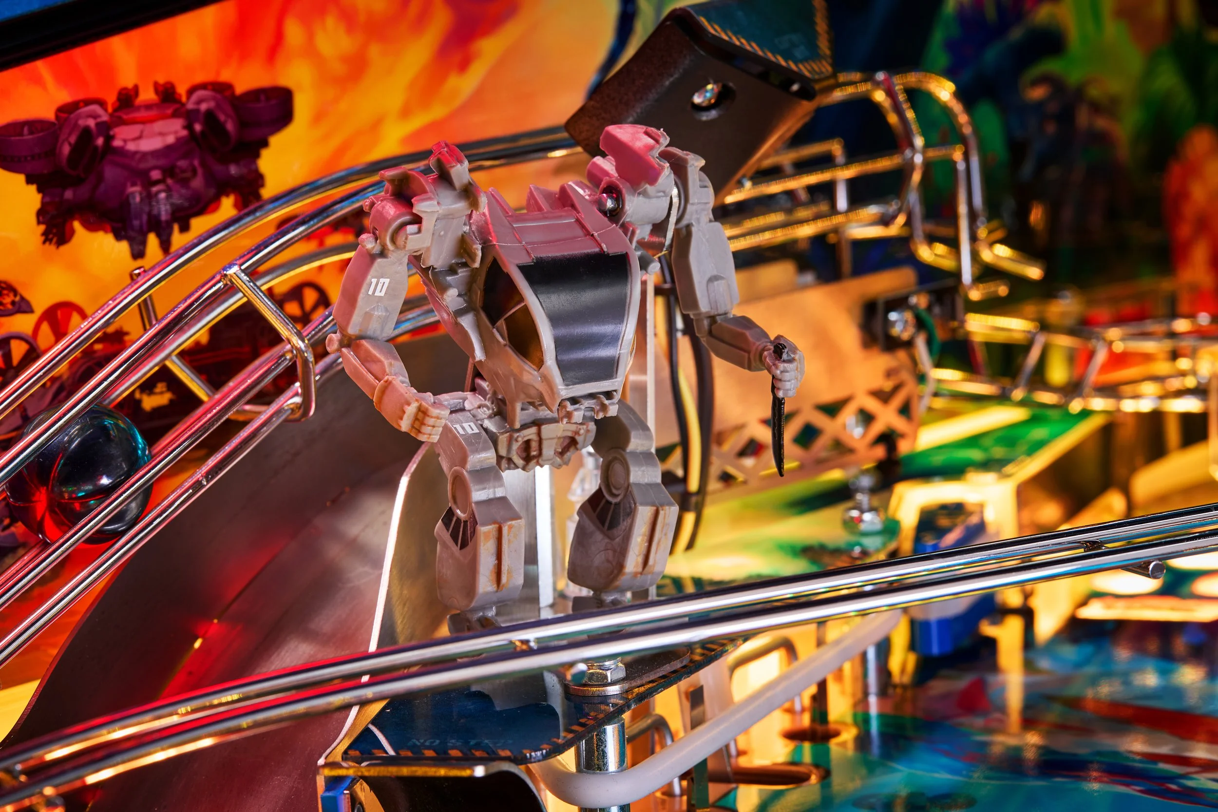 Close-up of a pinball machine featuring a robot figure and colorful artwork.