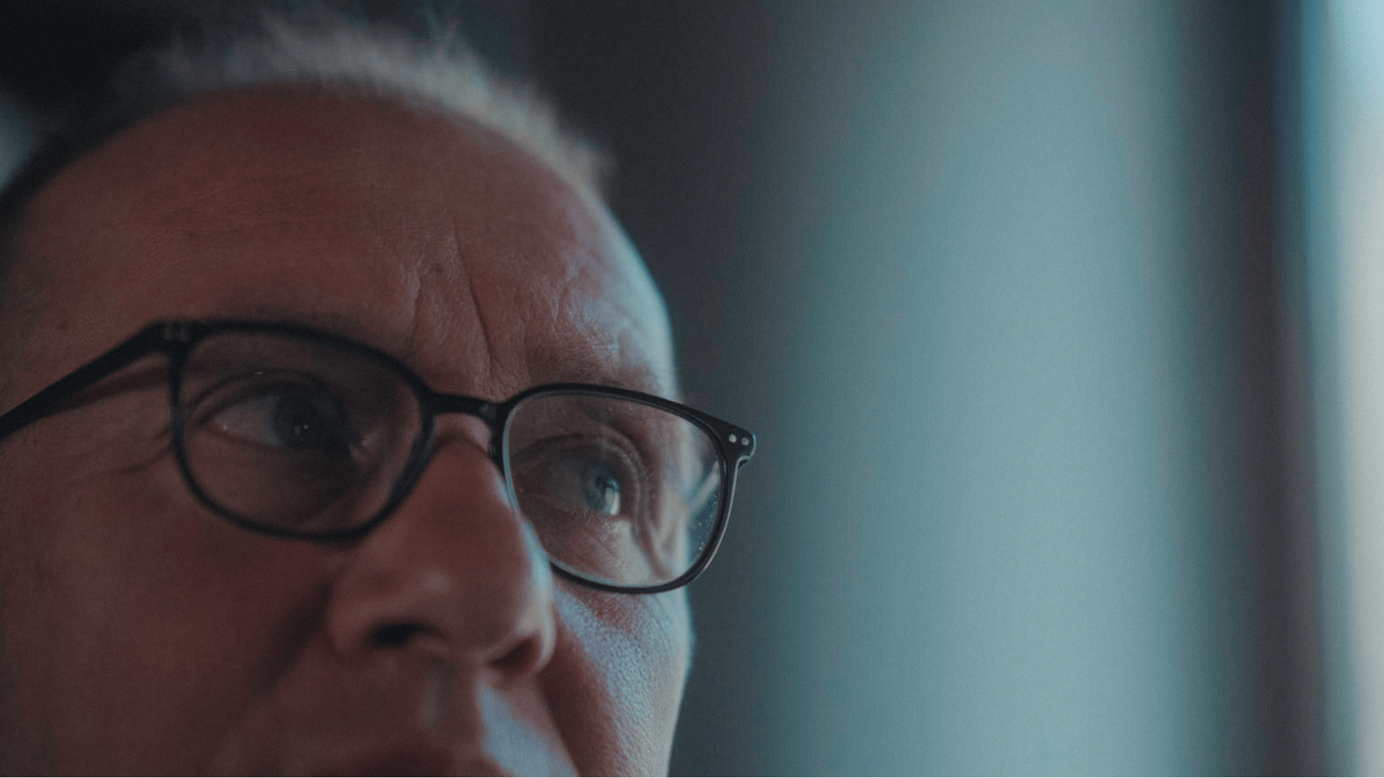 Nahaufnahme eines Mannes mit Brille, der nach oben schaut, nebelförmigem Licht.