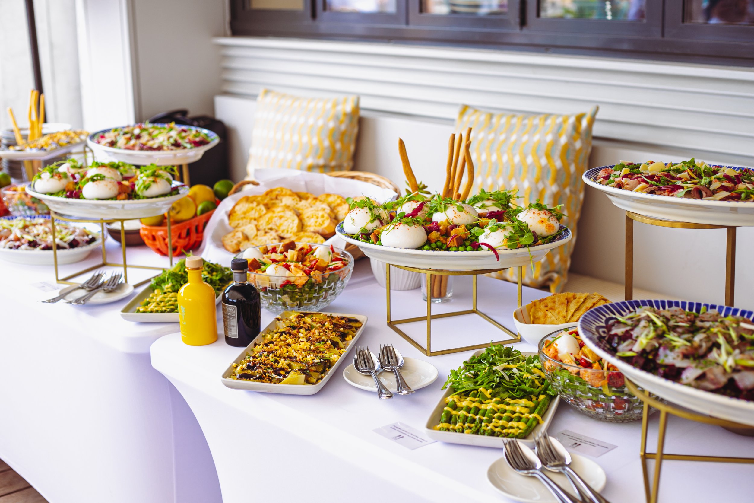Buffet de salades et plats variés avec des œufs mollets, légumes, et autres mets, décoré avec des assiettes et des sauces sur une table blanche