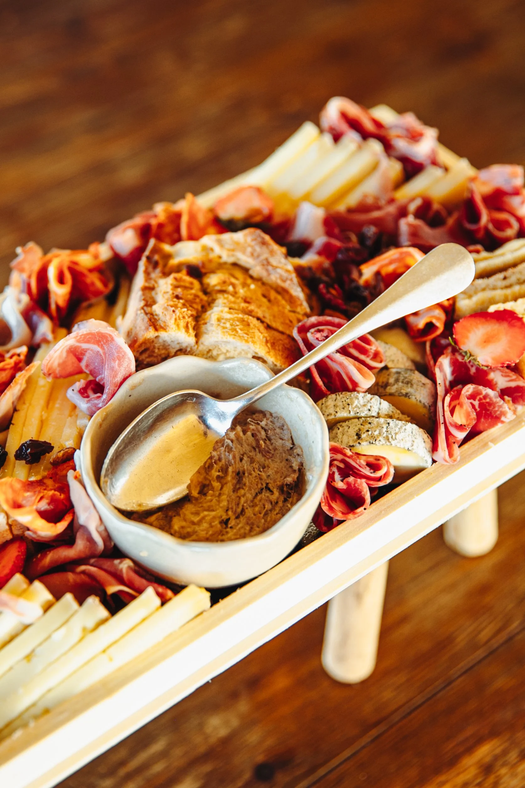Plate de charcuterie avec fromage, pain, fruits, et sauce de trempage.