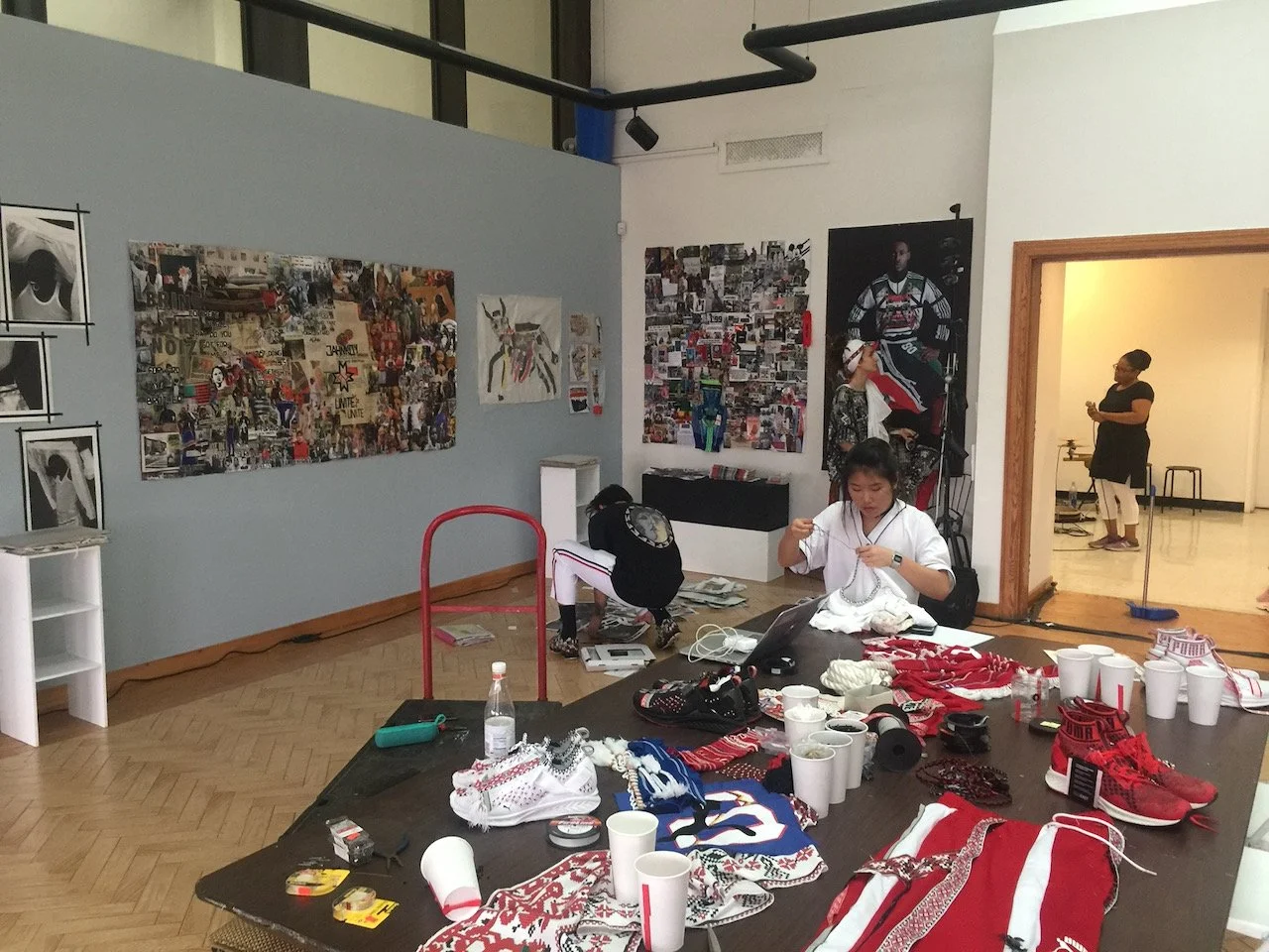 People working on arts and crafts in an art gallery with collage artwork on the walls.