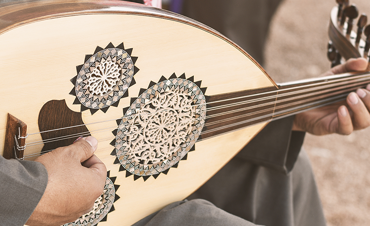 Close-up of a person playing an oud, a traditional Middle Eastern stringed instrument, with intricate sound hole designs.