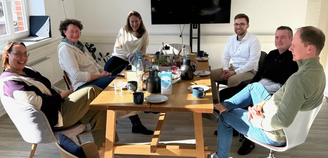 eine Gruppe sitzt an einem gedeckten Frühstückstisch