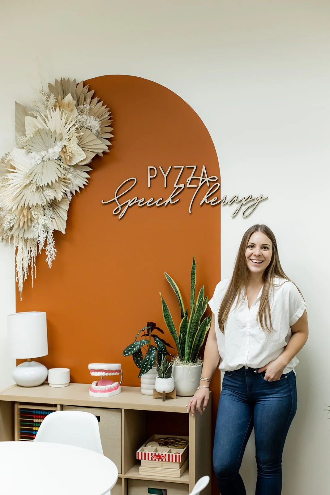 Gabby Pyzza, speech therapist in Phoenix, AZ, standing beside the Pyzza Speech Therapy office sign
