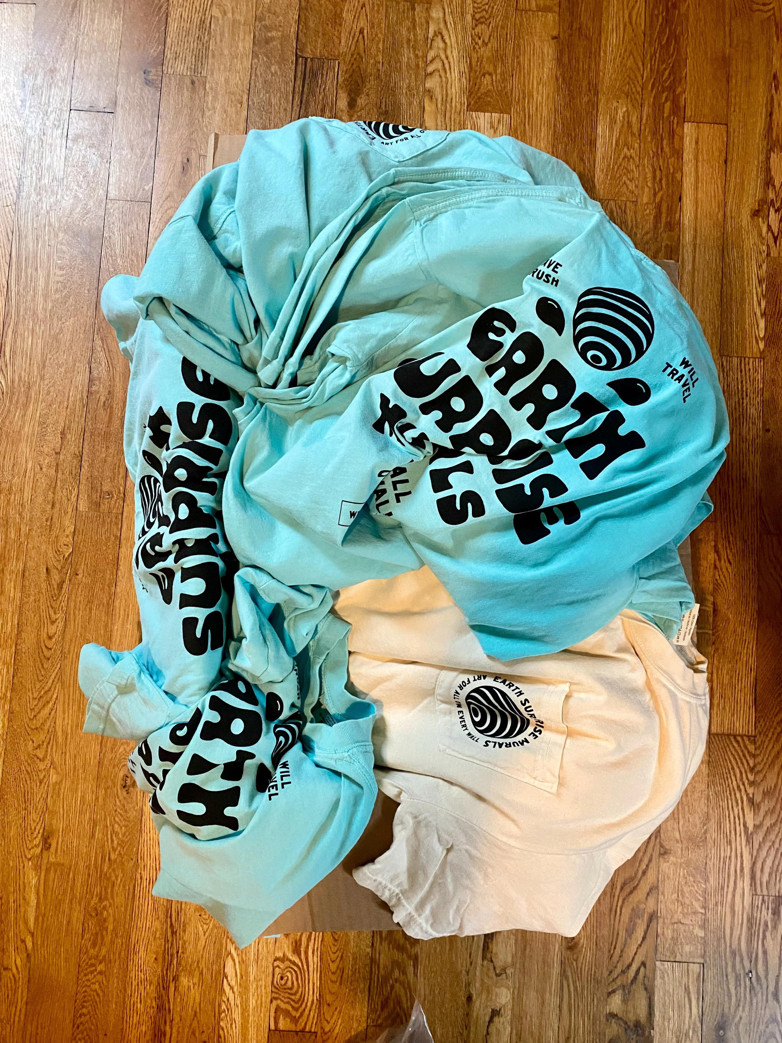 A bundle of earth supply company bags and a yellowish cloth on a hardwood floor.