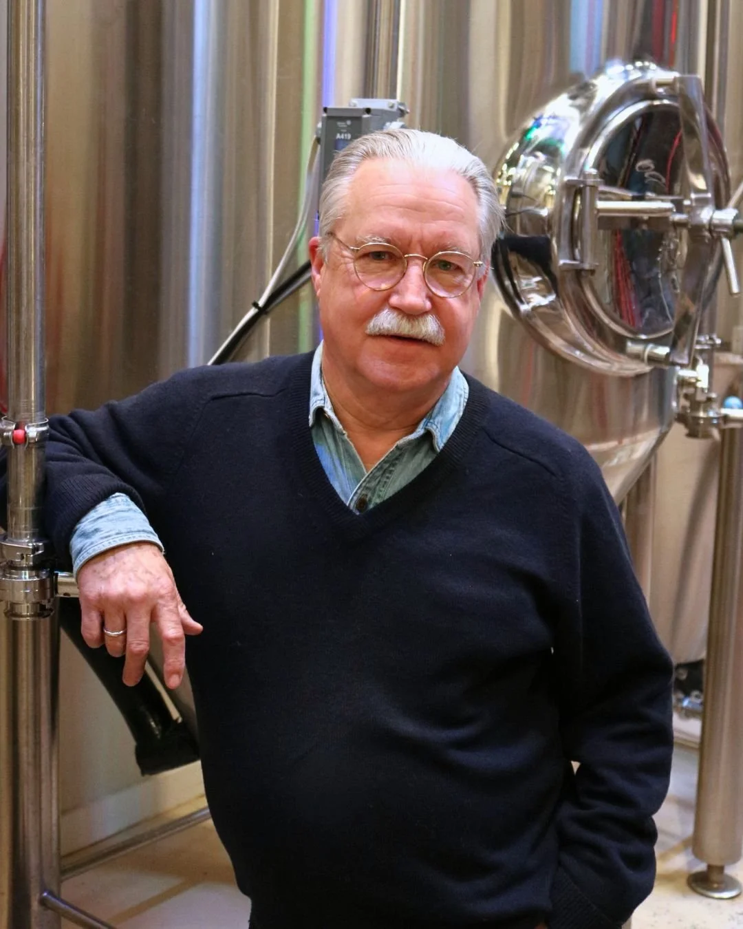 Headshot of Andy Mason, in a plaid blue sweater inside the production facility