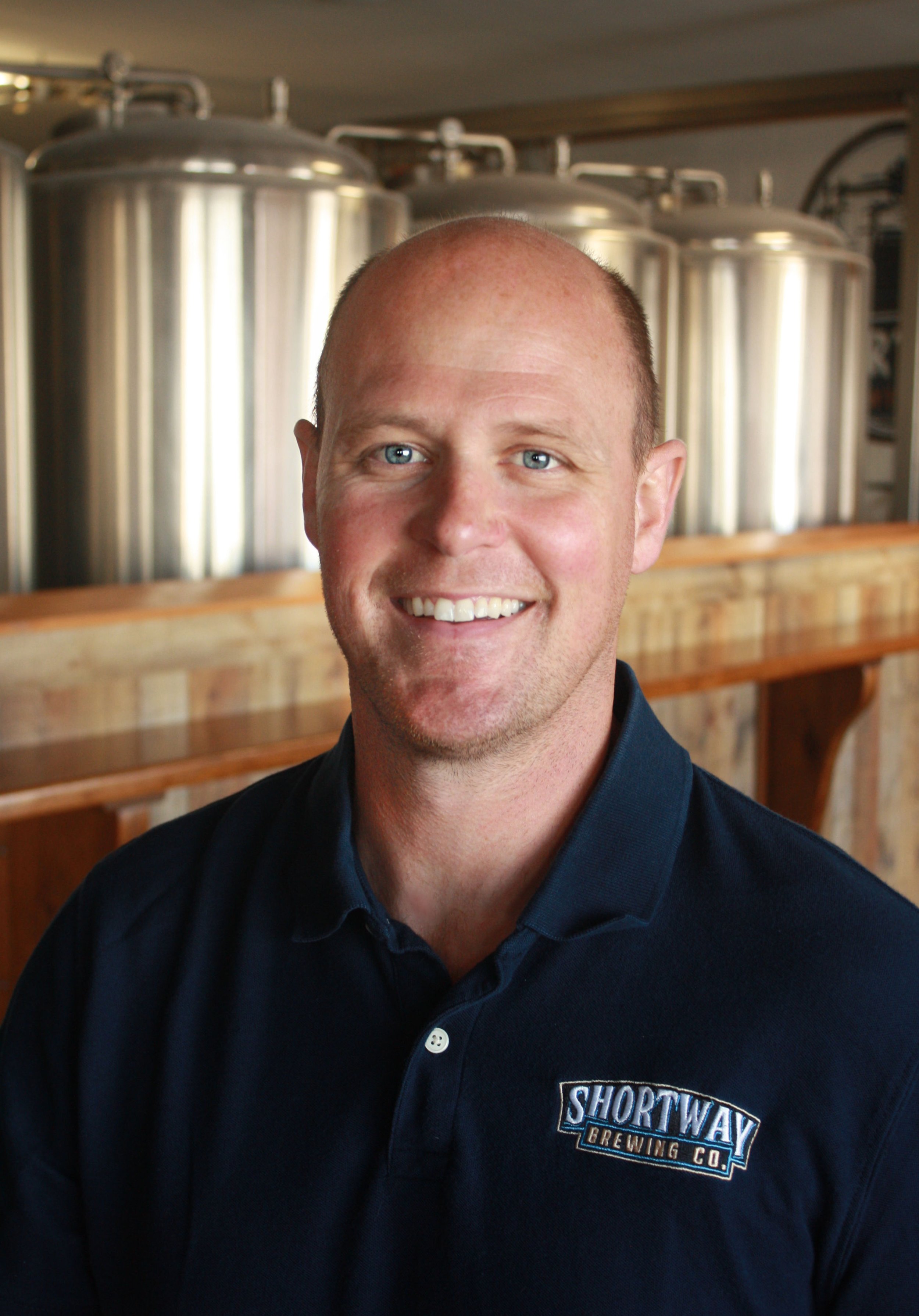 Headshot of Matt Shortway wearing a Shortway Brewing shirt with the brewery in the background