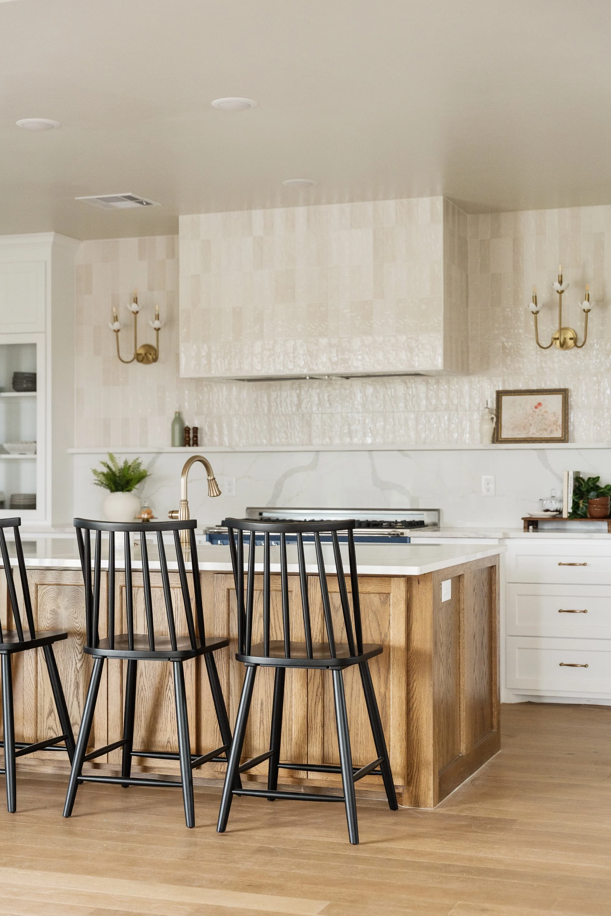 Modern kitchen with white upper cabinets, gray lower cabinets, a white countertop island, pendant lights, and a window above the sink.