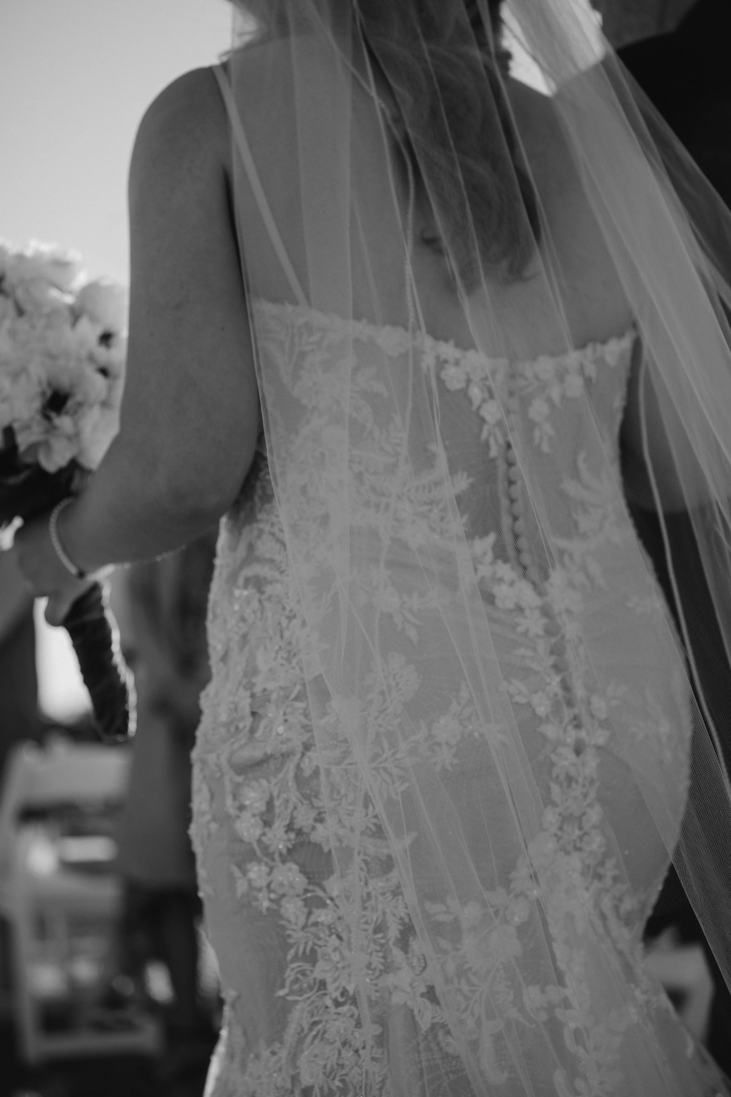 Bride in lace wedding dress holding bouquet, black and white photo