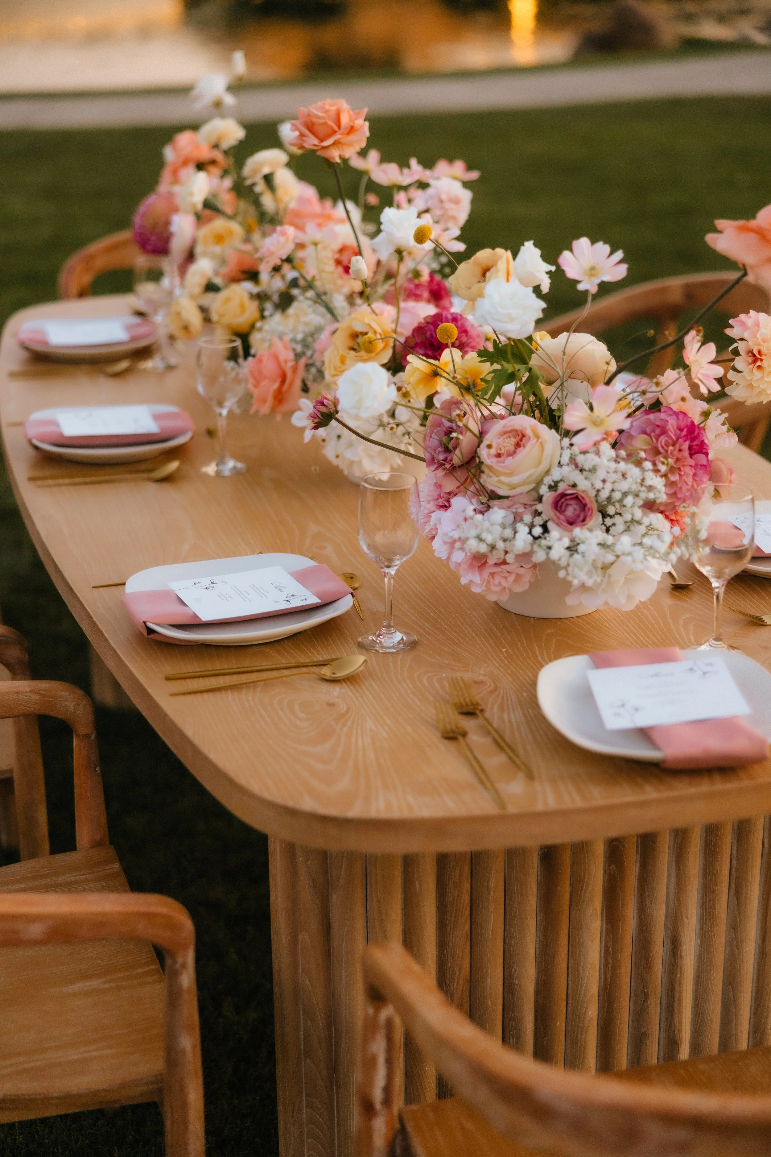 Elegant wedding table setting with flowers, pink napkins, and menus