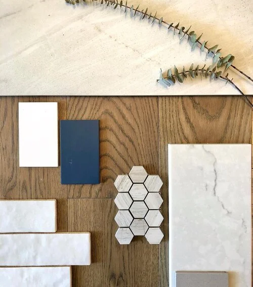 Arrangement of various tiles and a dried eucalyptus branch on a wooden surface.