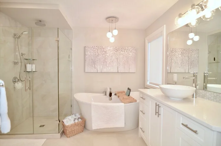 Bright bathroom with a walk-in shower, bathtub with a tray and tablet, white vanity with a vessel sink, large mirror, and decorative picture on the wall