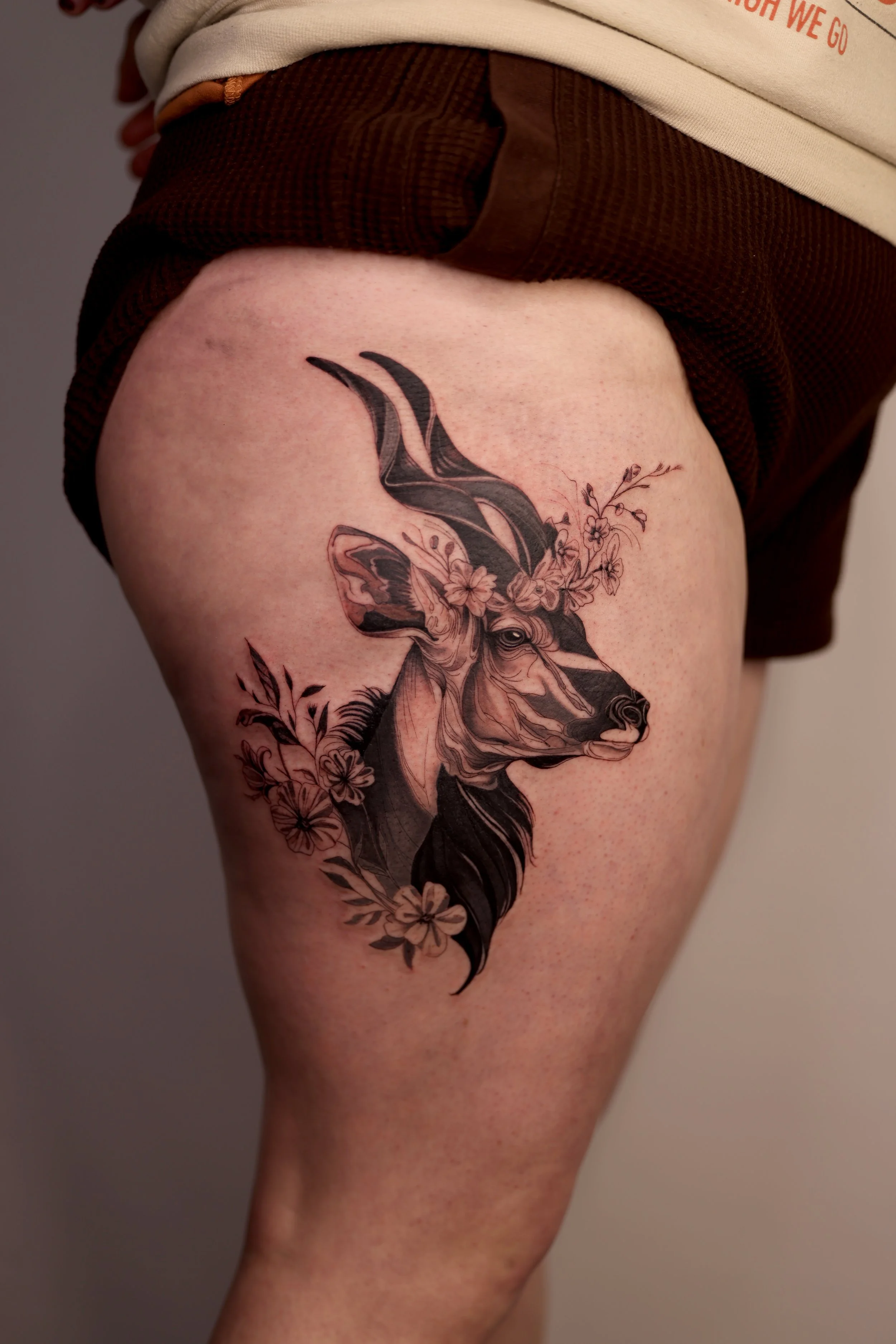 Ryane Rose antelope tattoo on the thigh/hip with floral work surrounding the animal