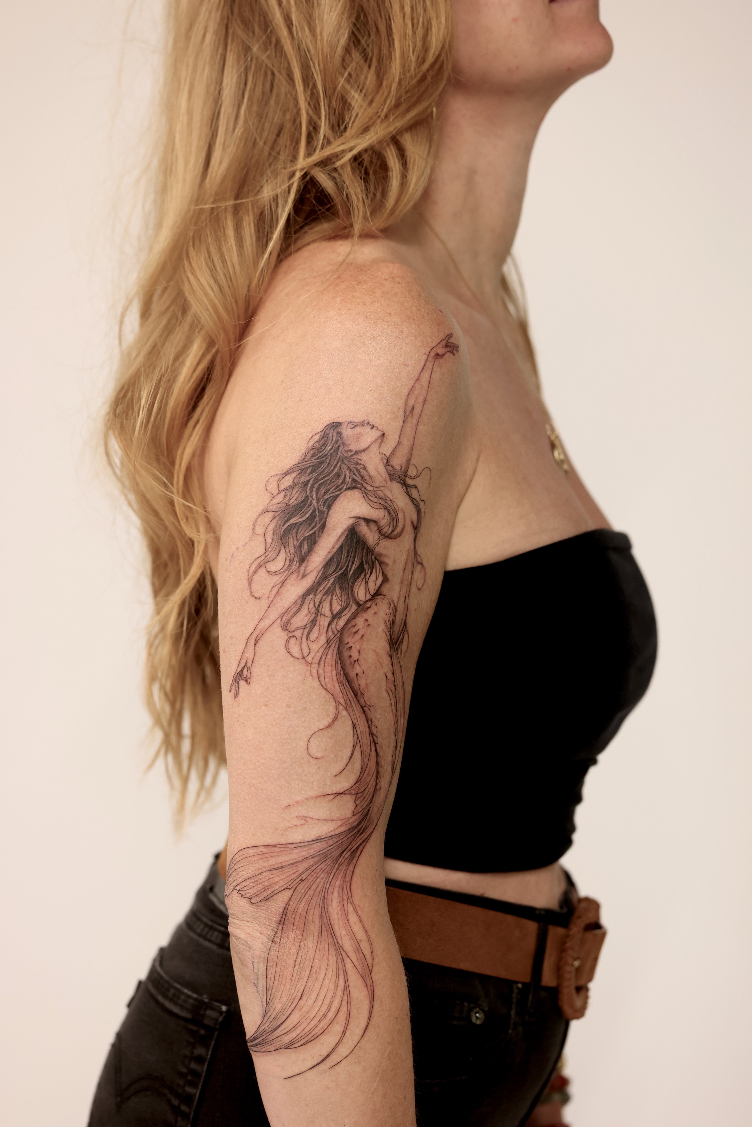 A stunning whimsical mermaid tattoo that is feminine and soft. This tattoo starts at the shoulder and the fin works it way down by the elbow