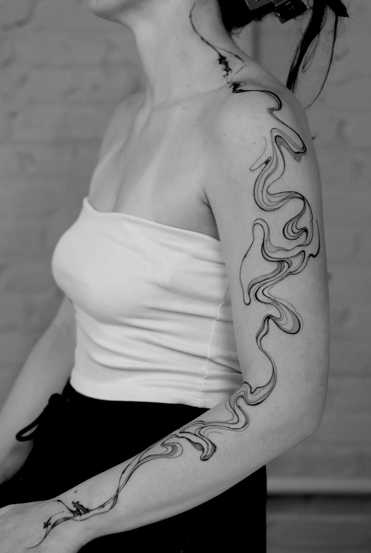 An abstract line work tattoo that trails from the neck all the way down to the client's wrist.