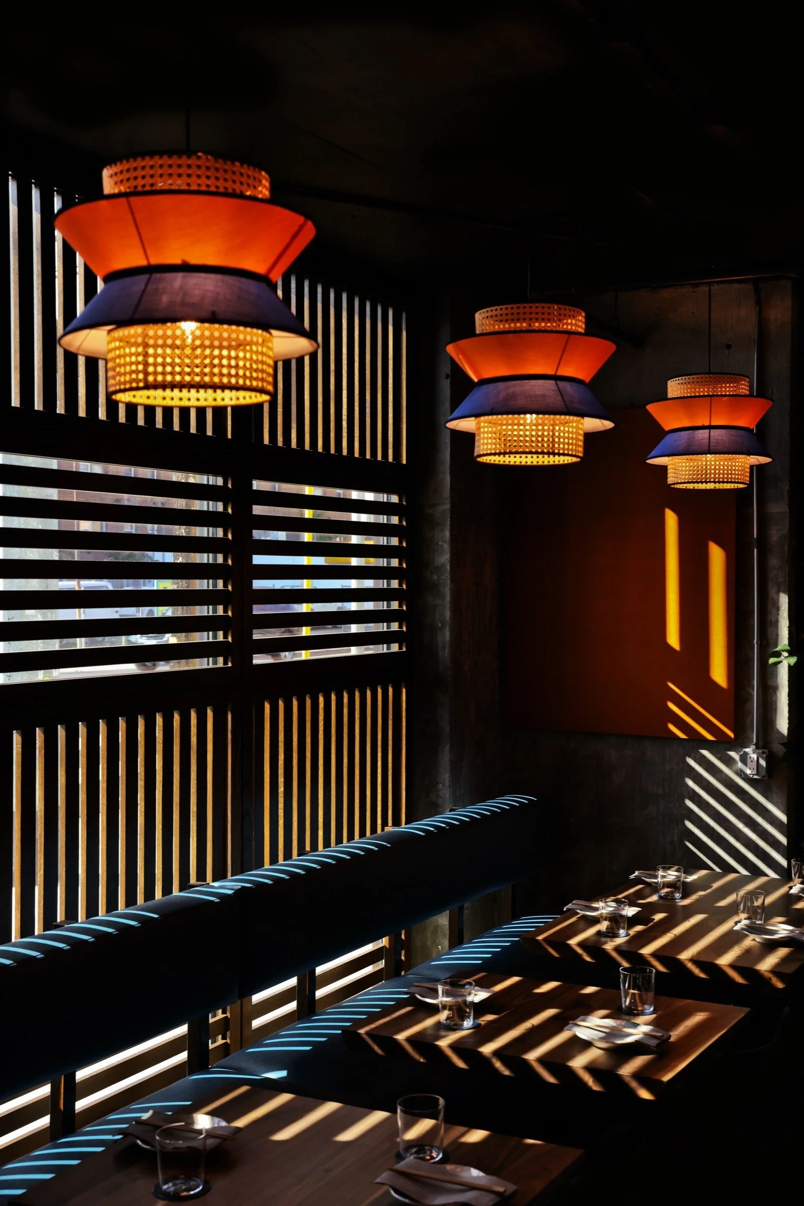 Budonoki dining room with rattan pendant lanterns and slatted wood walls