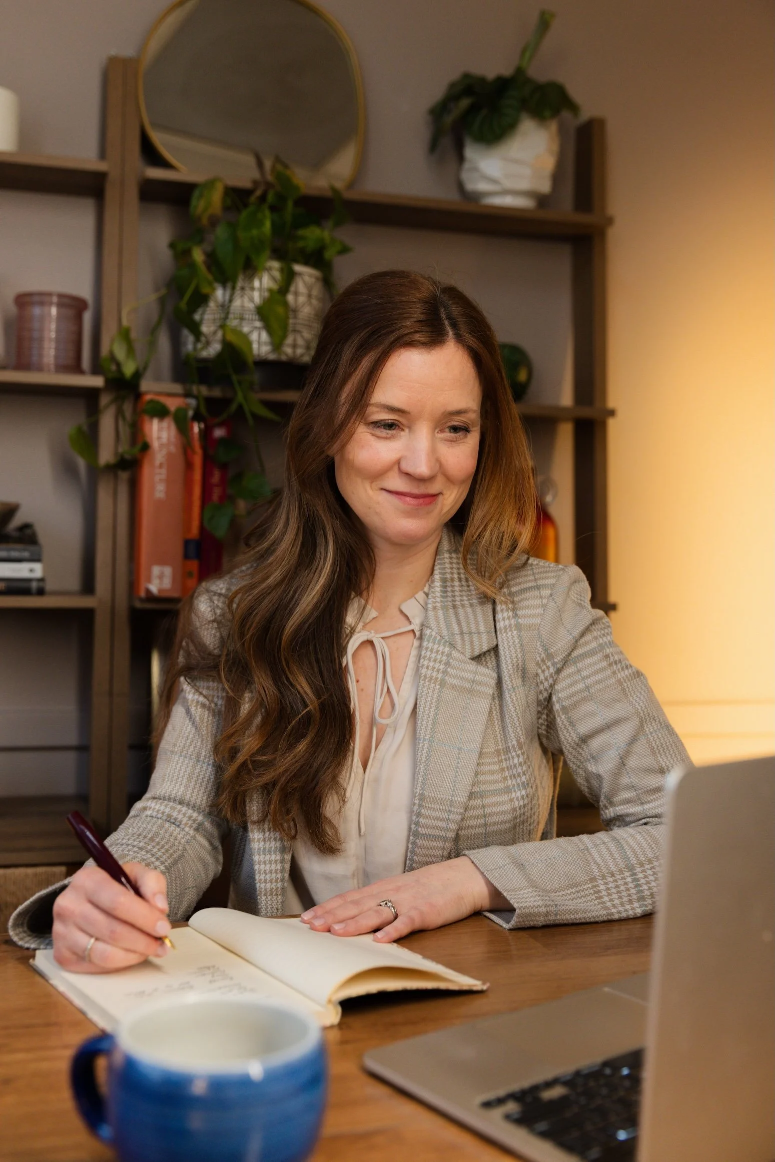 woman sitting at her desk writing notes during a virtual functional health meeting