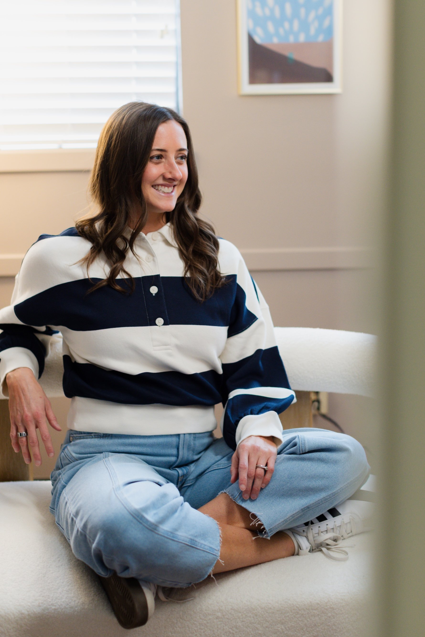 woman sitting cross legged on a modern couch in an office setting