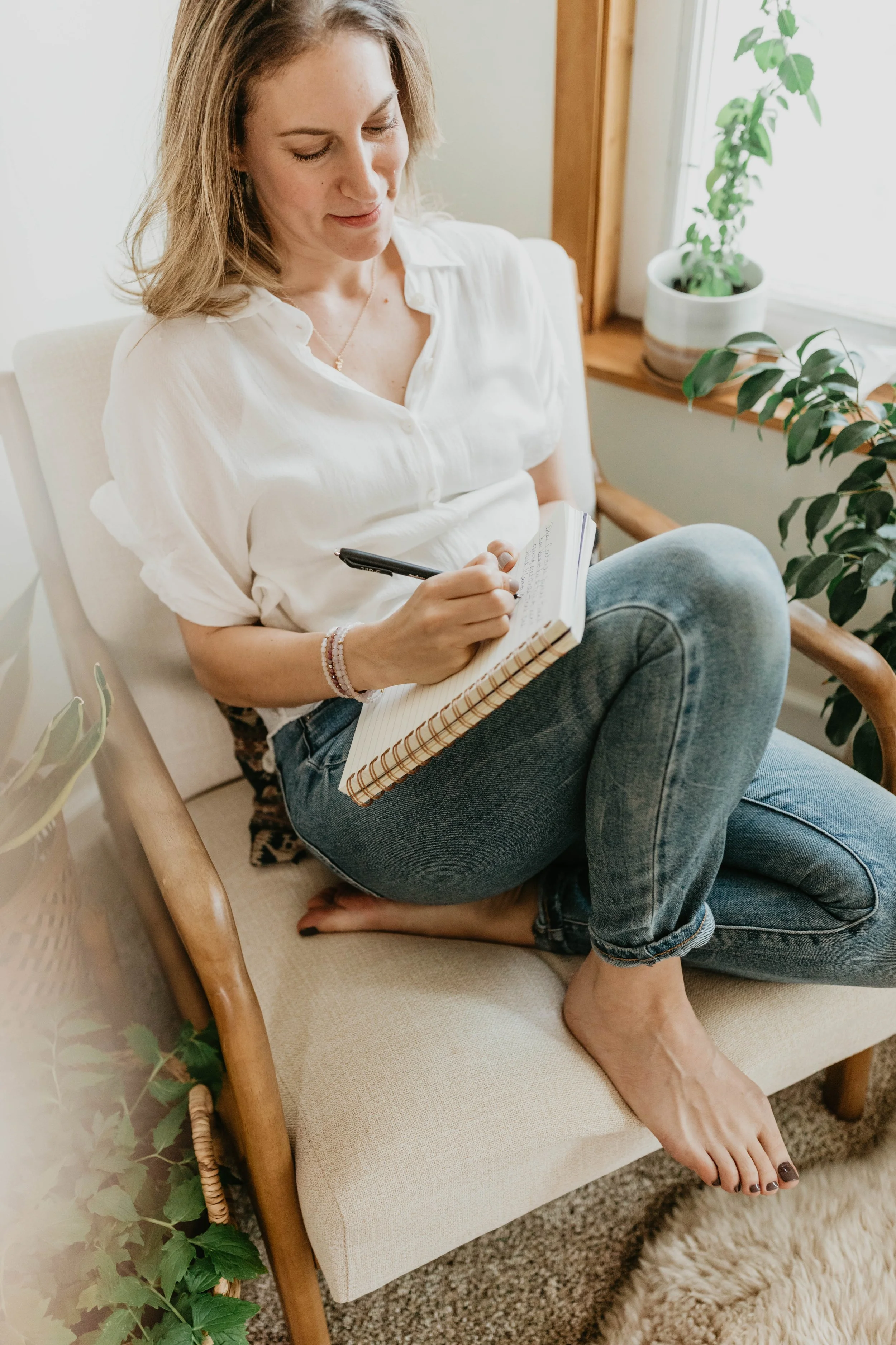 woman sitting in a chair writing in a notebook