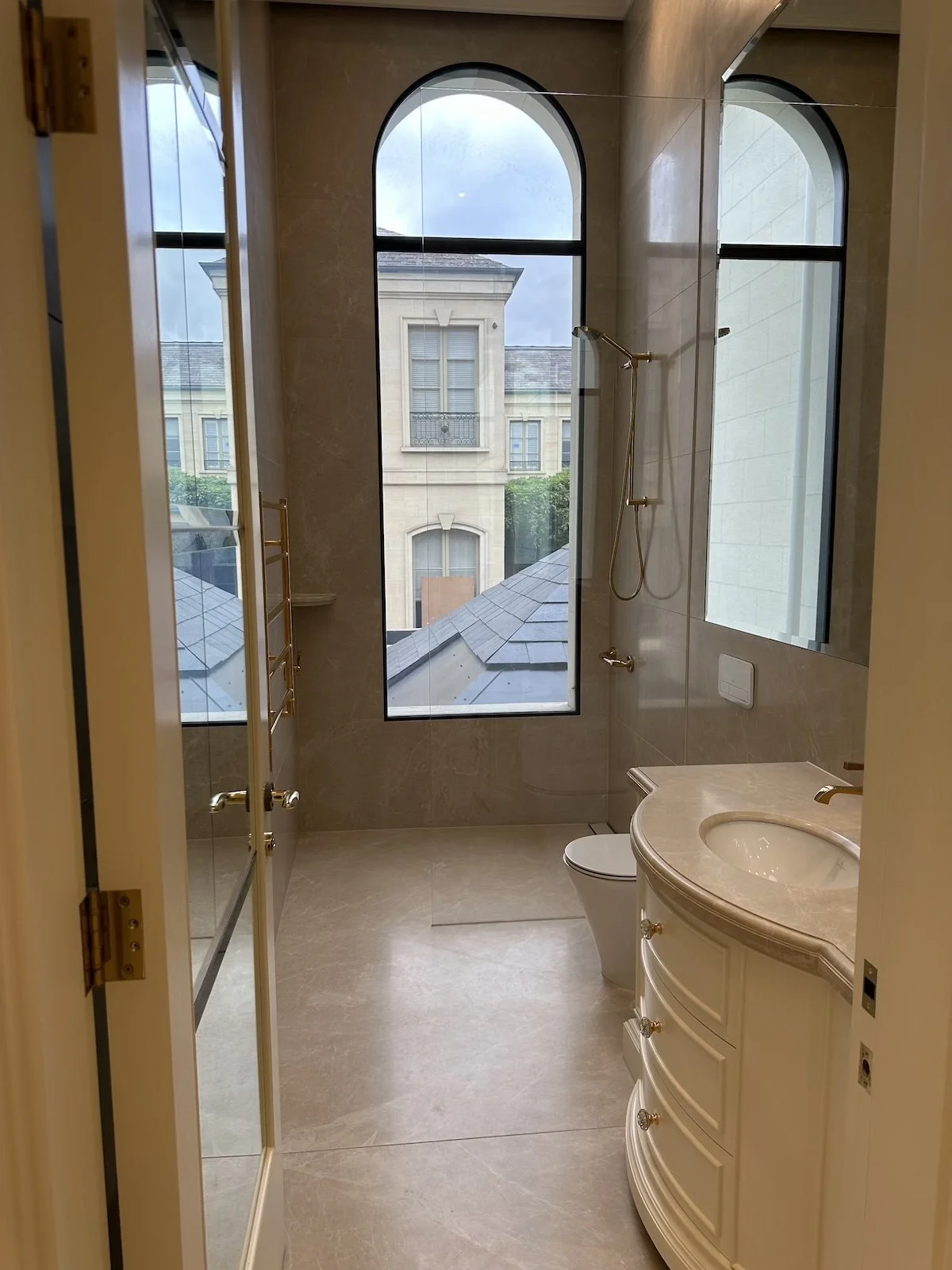 Modern bathroom with glass shower, white tiled walls, vanity with blue cabinets, and decorative plants.