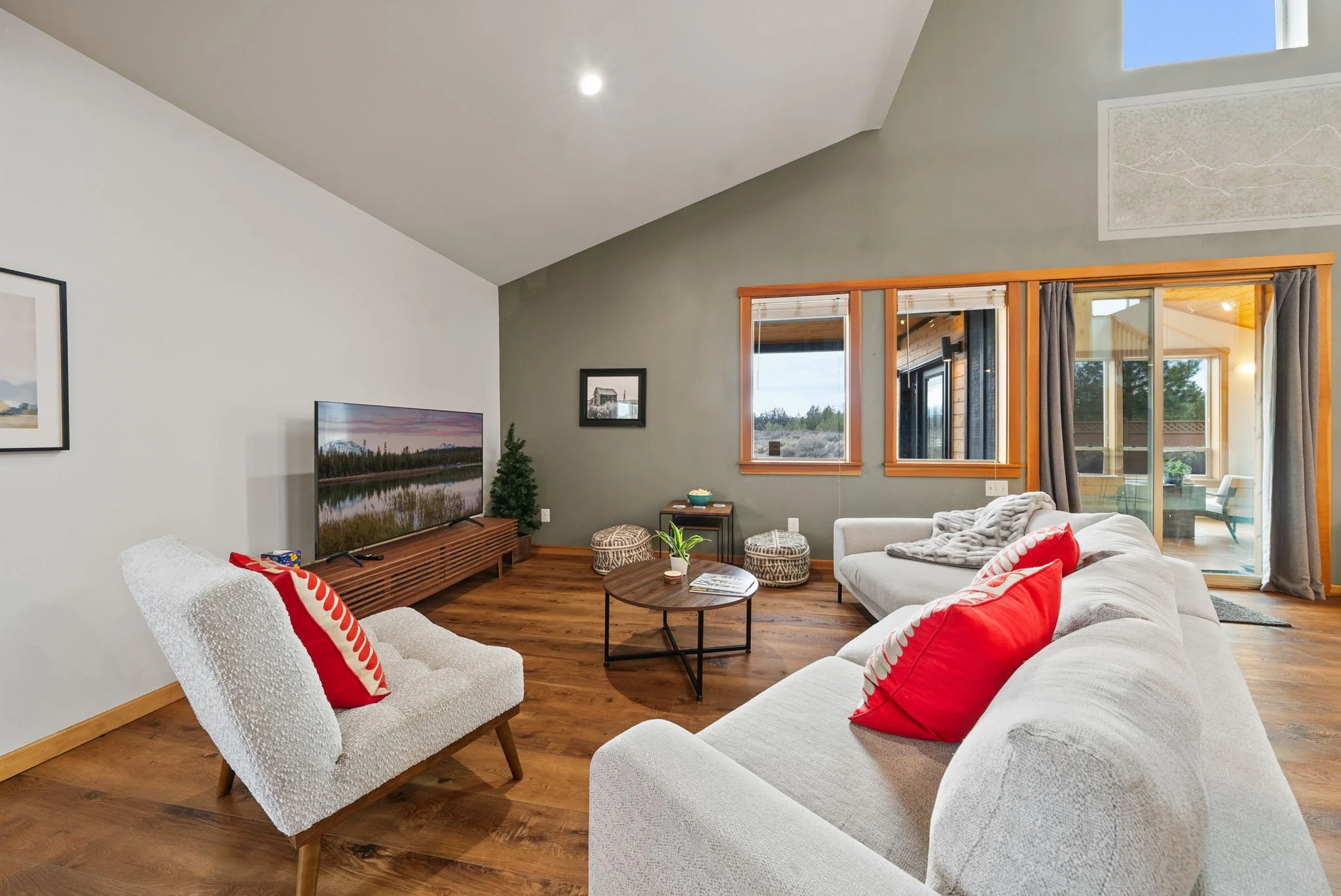 A photo looking from living room area to the sun room with windows showing a view of the mountains