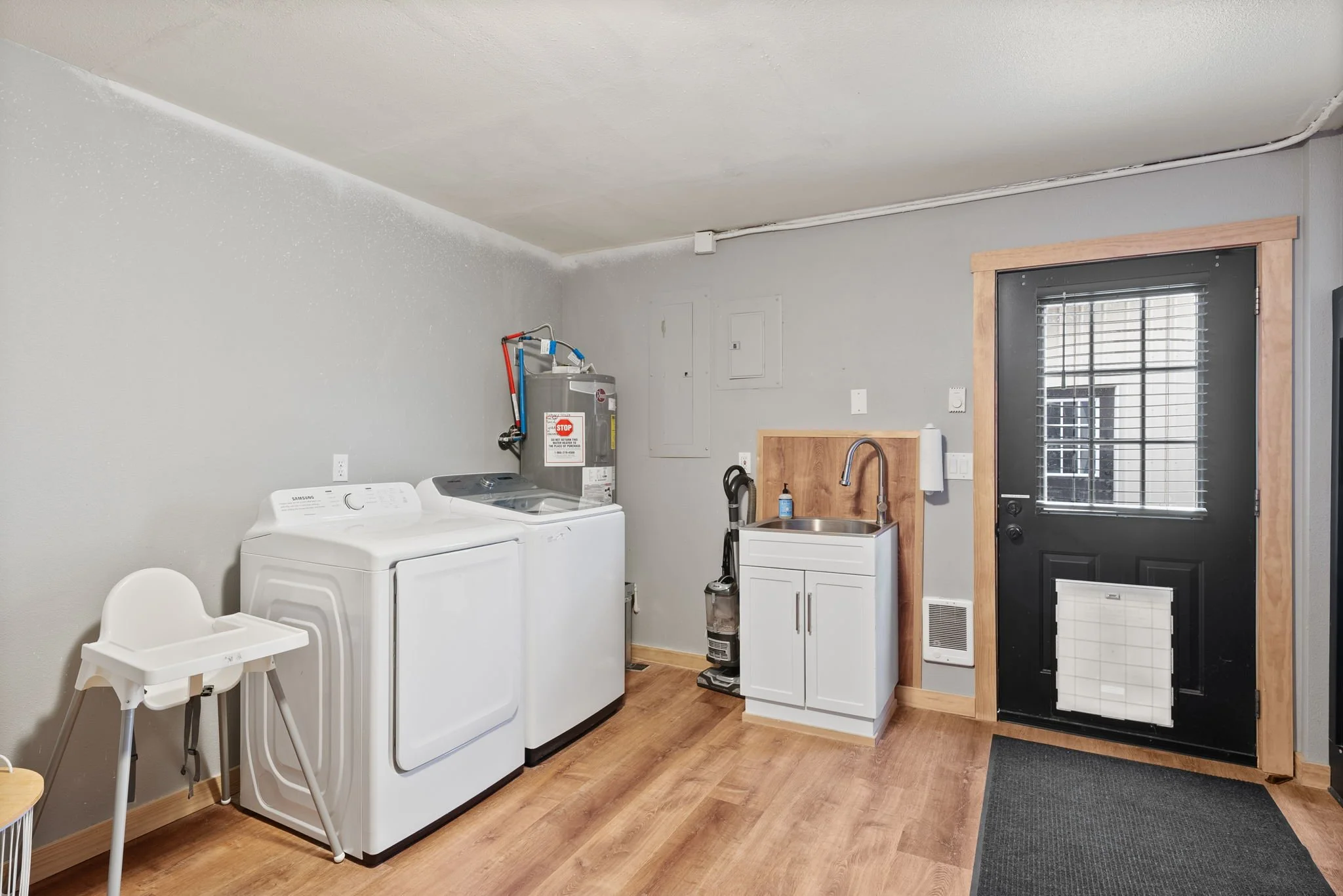Main floor laundry room with washer, dryer and high chairs