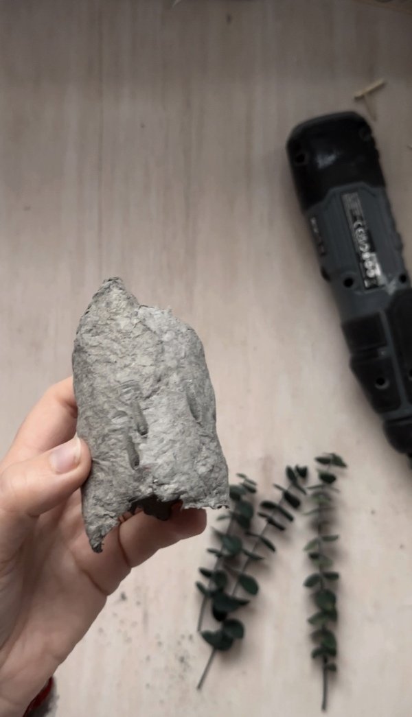 Close-up of a dried paper pulp napkin ring with drilled holes, ready for attaching botanical elements in a DIY project.