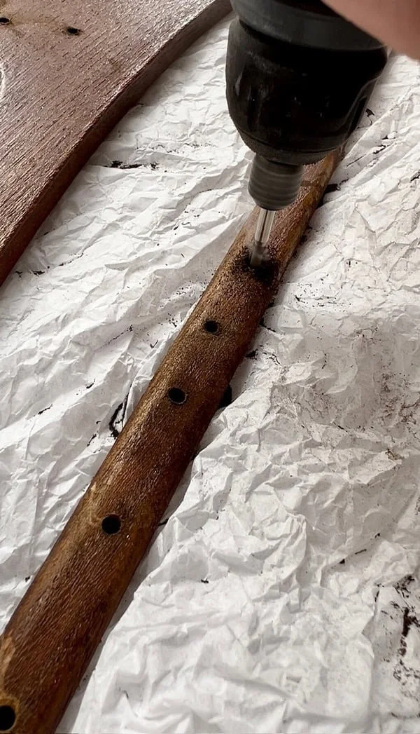 Close-up of a rotary tool drilling holes through a wooden hanger for a DIY jewellery hanger project.