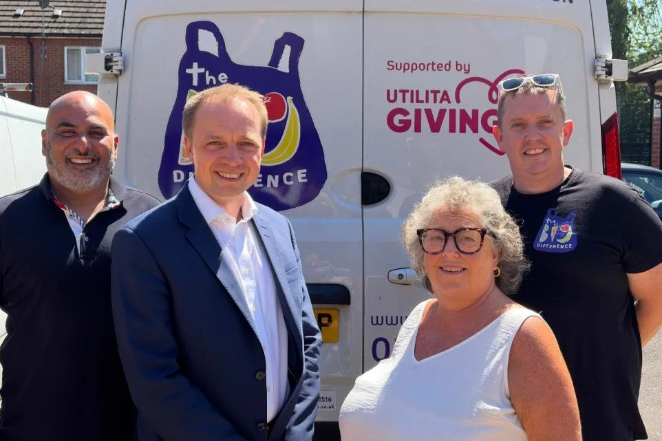 Four smiling people standing in front of a white van with logos and text, including 'Supported by Utilita Giving' and a shopping bag graphic with the words 'the Difference' on it.