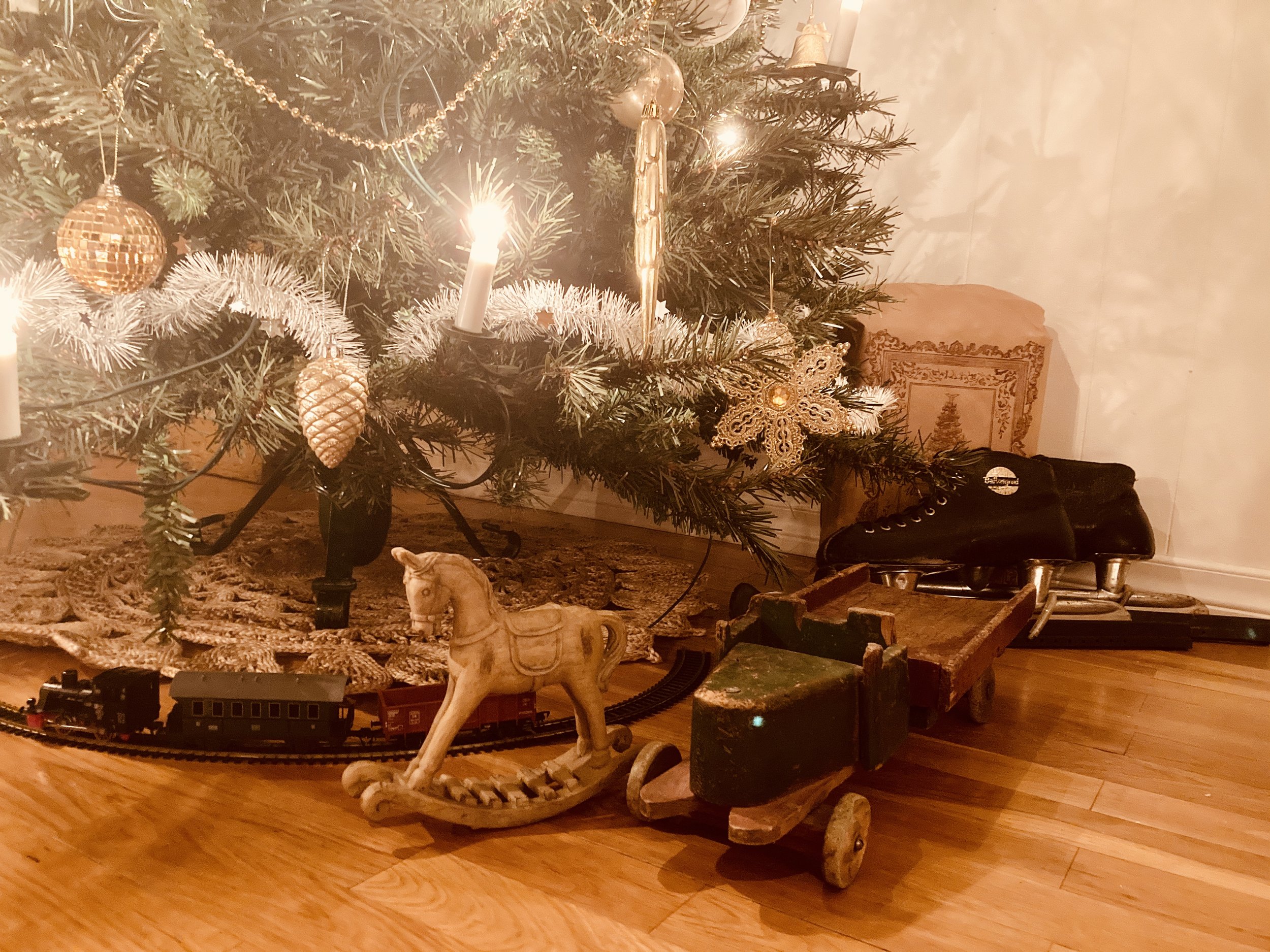 Nostalgisk juletre med trebil, skjøyter, tog og liten gyngehest under.