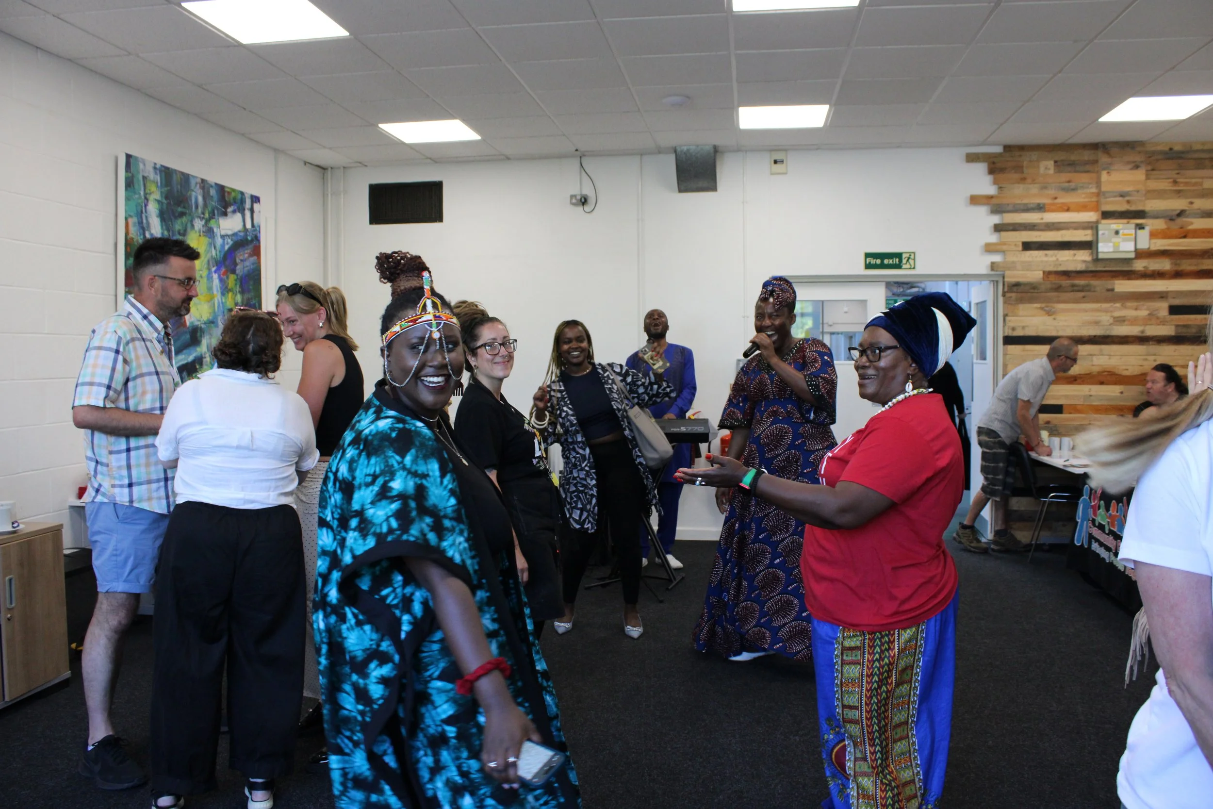 Celebrating Refugee Week, people smiling and enjoying a gathering in our Taylor Suit, celebrating together