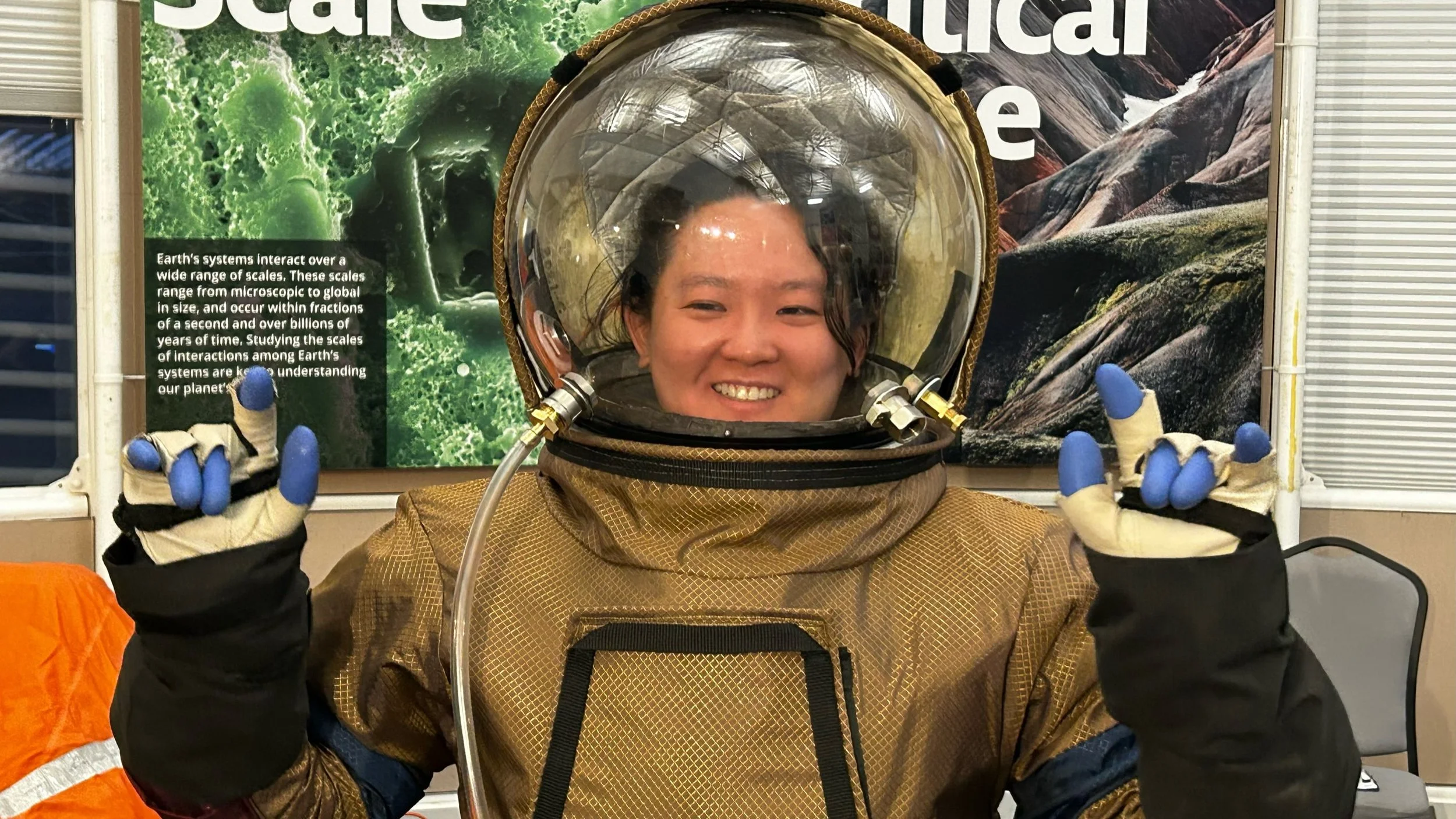 Sheila signs using ASL while wearing a space suit and completing analog space training.