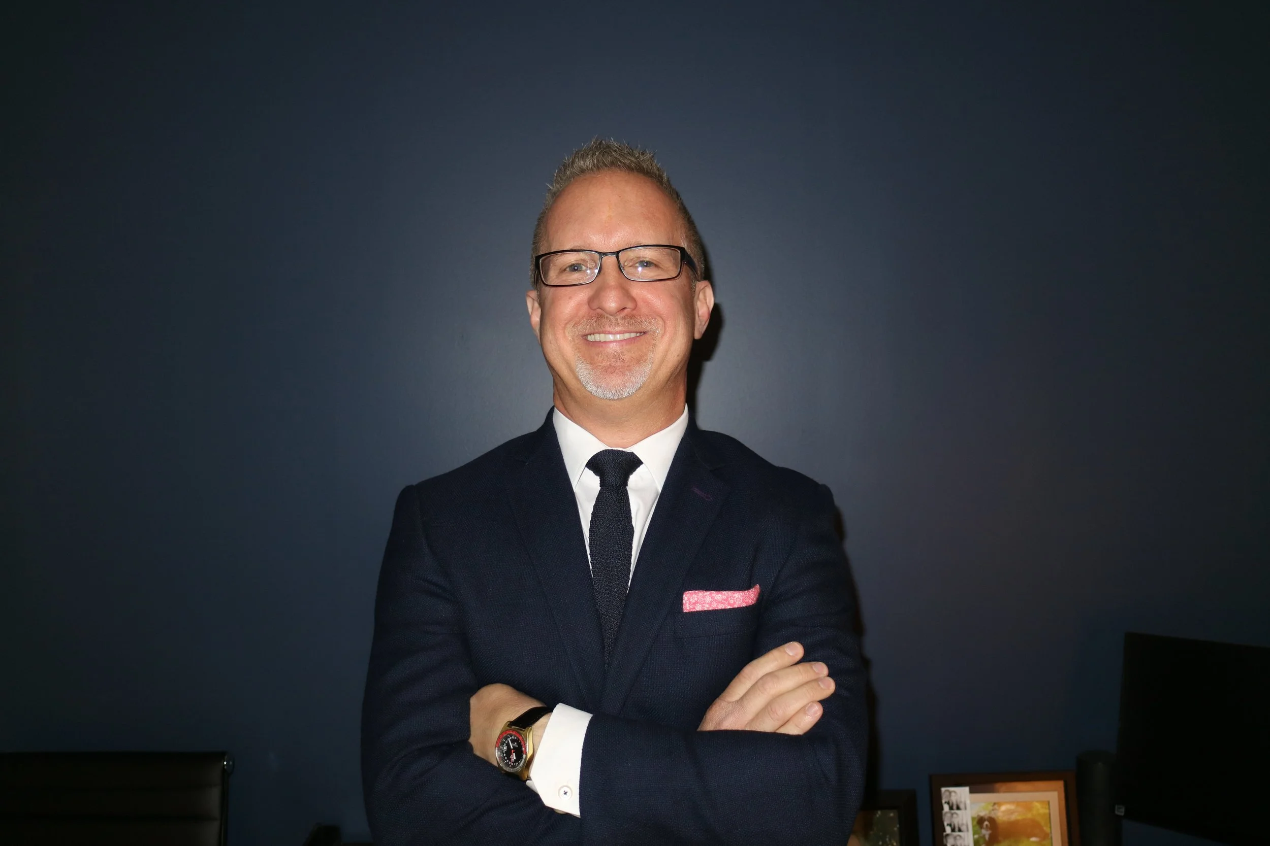 Jeff wears a suit and tie and glasses, smiling at the camera in a professional headshot.