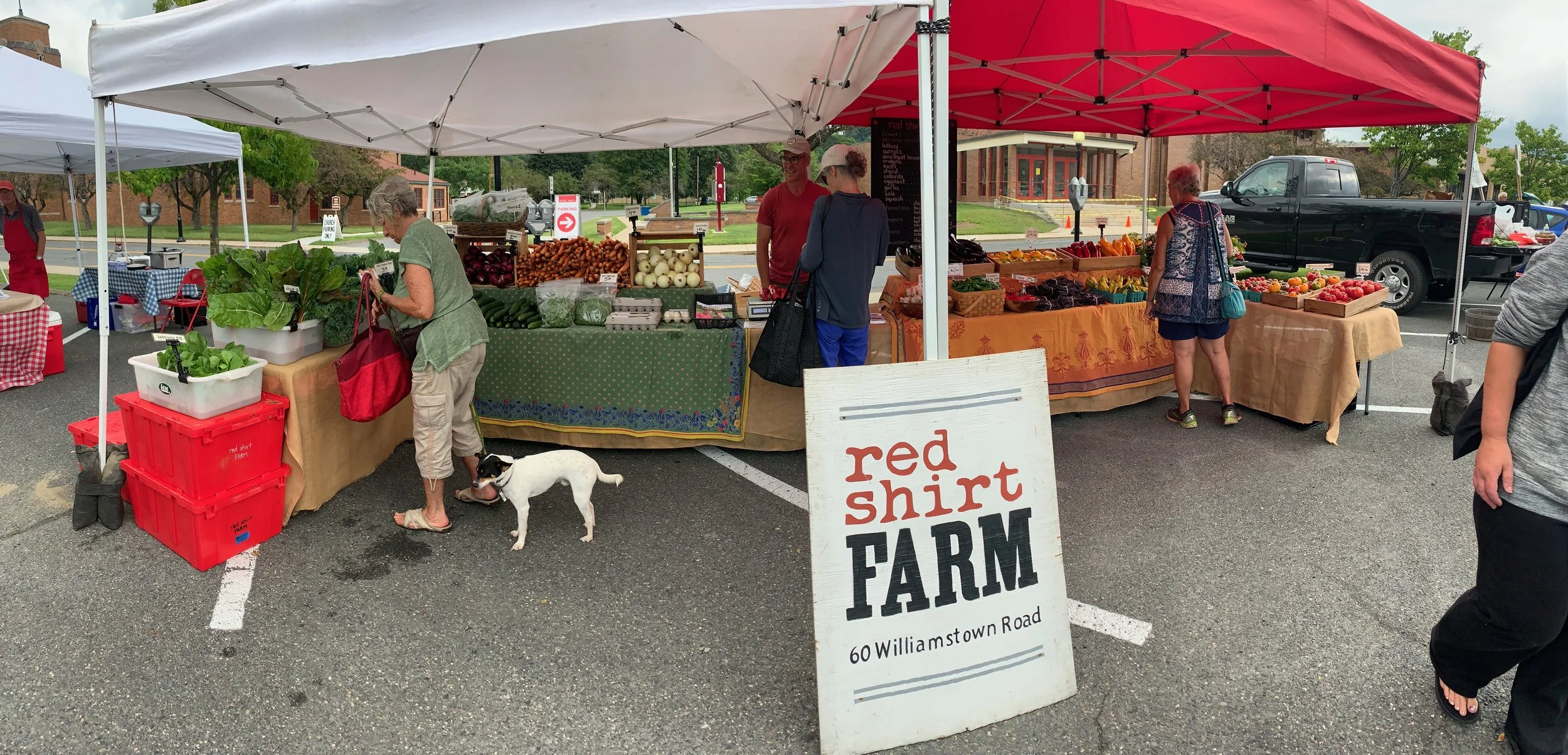 Red Shirt Farm stand at a farmers market with a farm sign