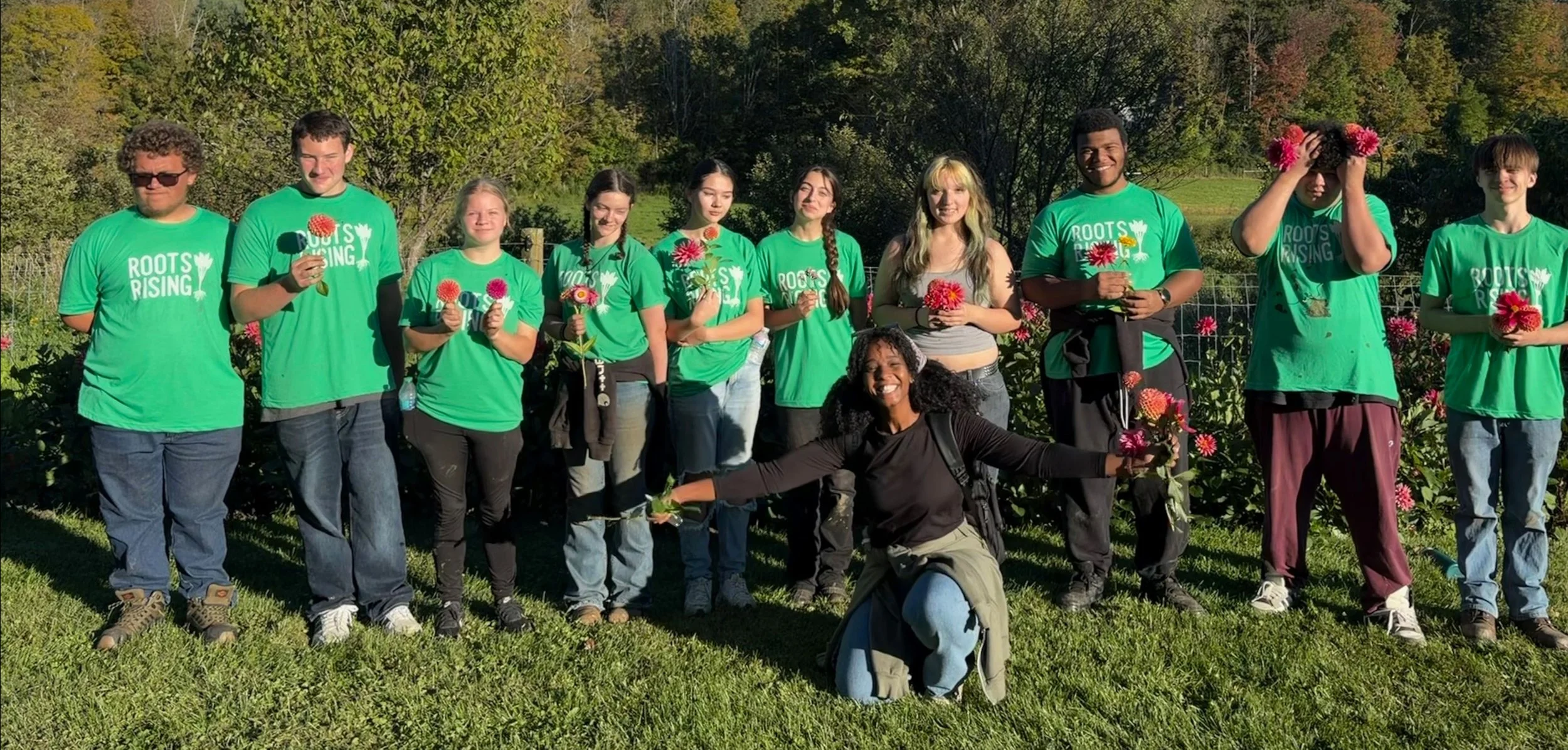 A Roots Rising crew in green t-shirts posing together in the field at Red Shirt Farm