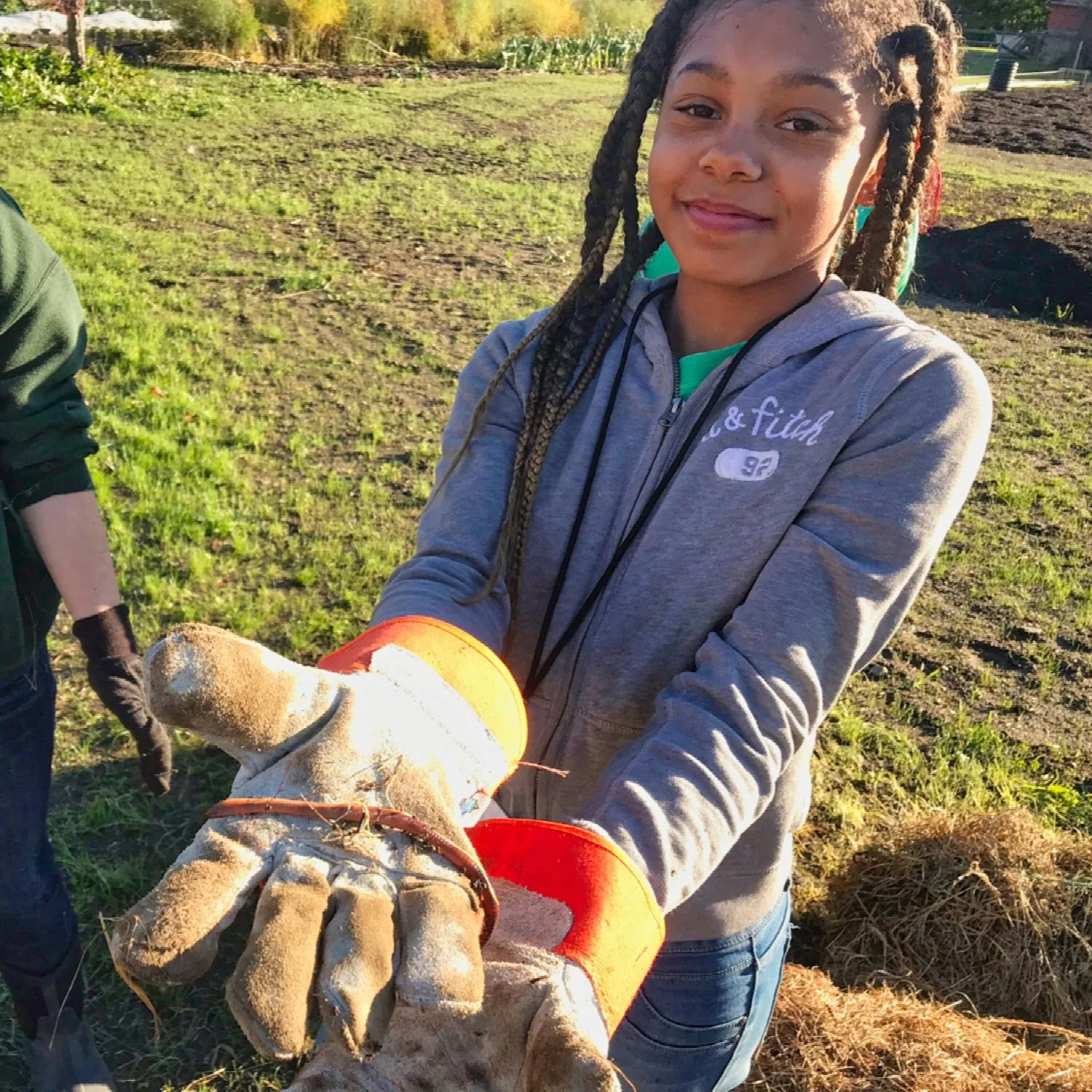 A Roots Rising student holds out a gloved hand at a field session at Red Shirt Farm