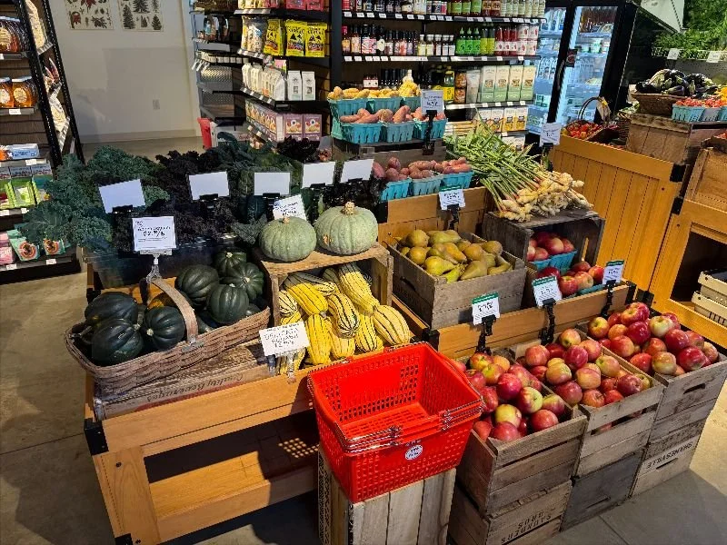 A farm store display of kale, winter squash, sweet potatoes, apples and ginger in wooden crates