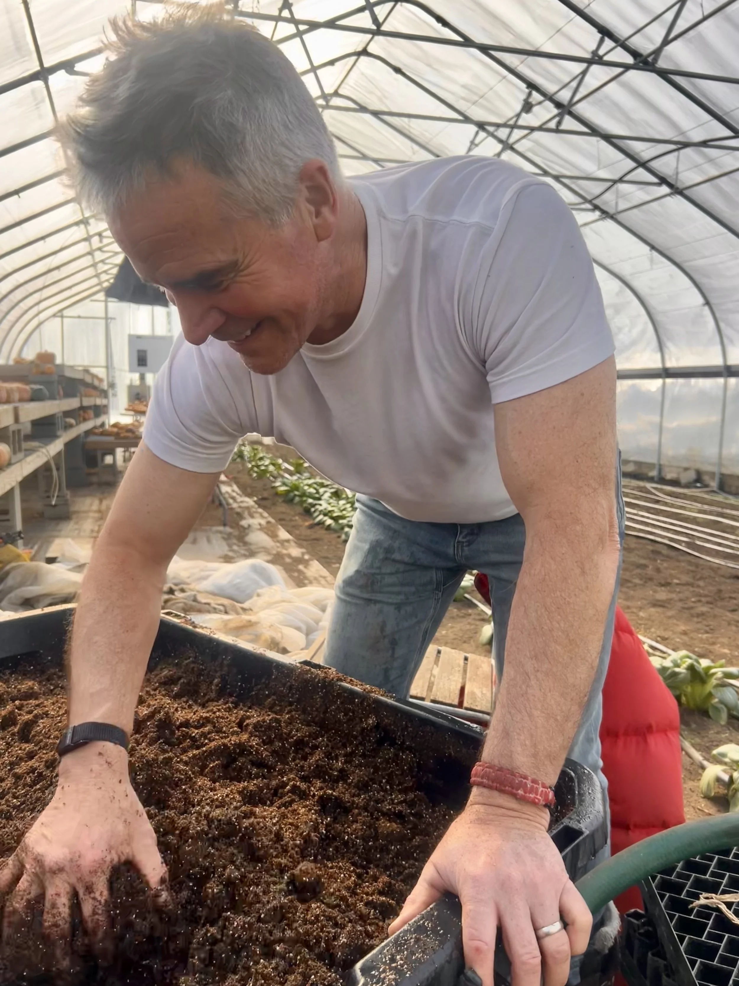 Jim, the farmer at Red Shirt Farm, mixing organic potting soil in the greenhouse to prepare seedling starts for the spring plant sale